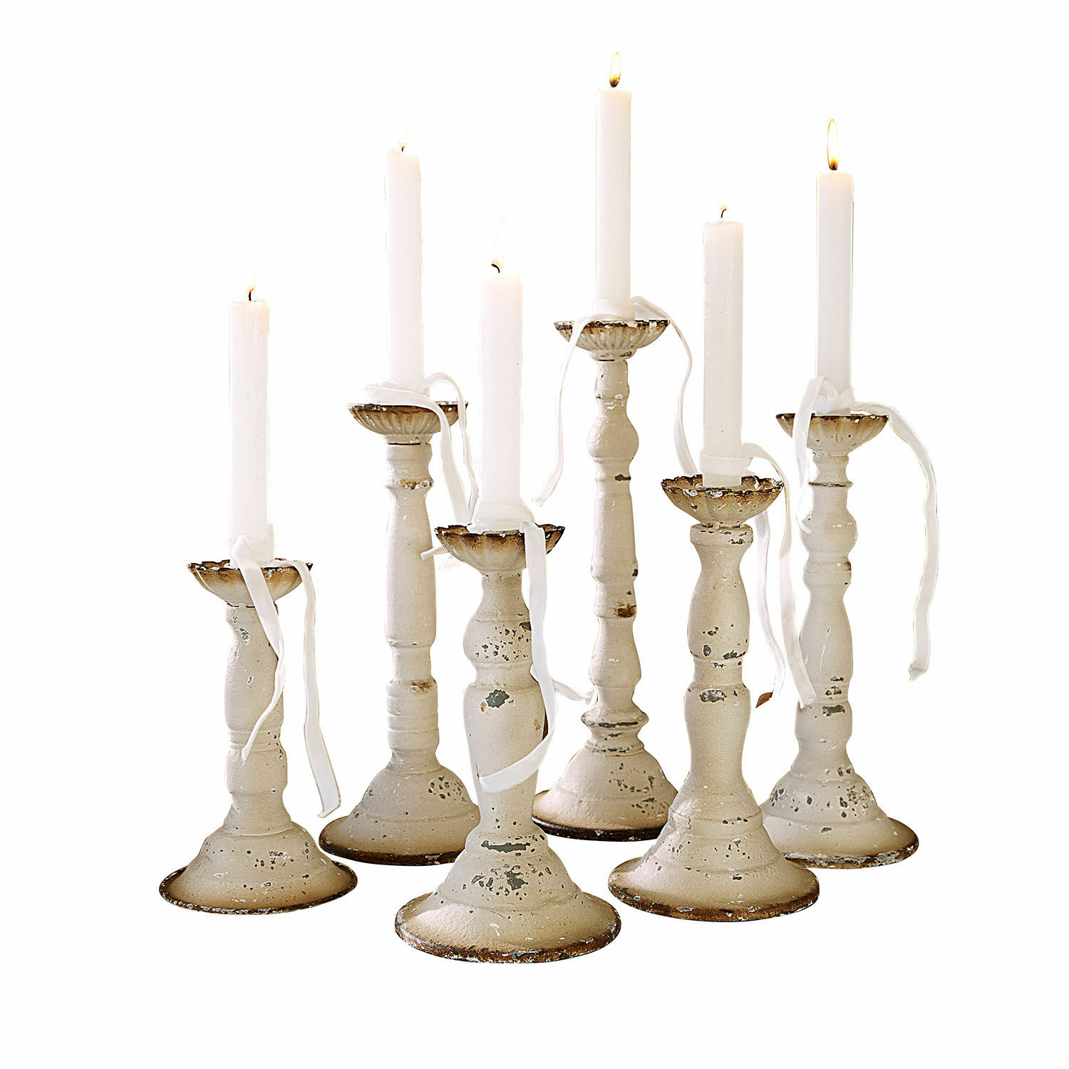 Conjunto de siete candelabros de metal blanco envejecido con velas blancas encendidas