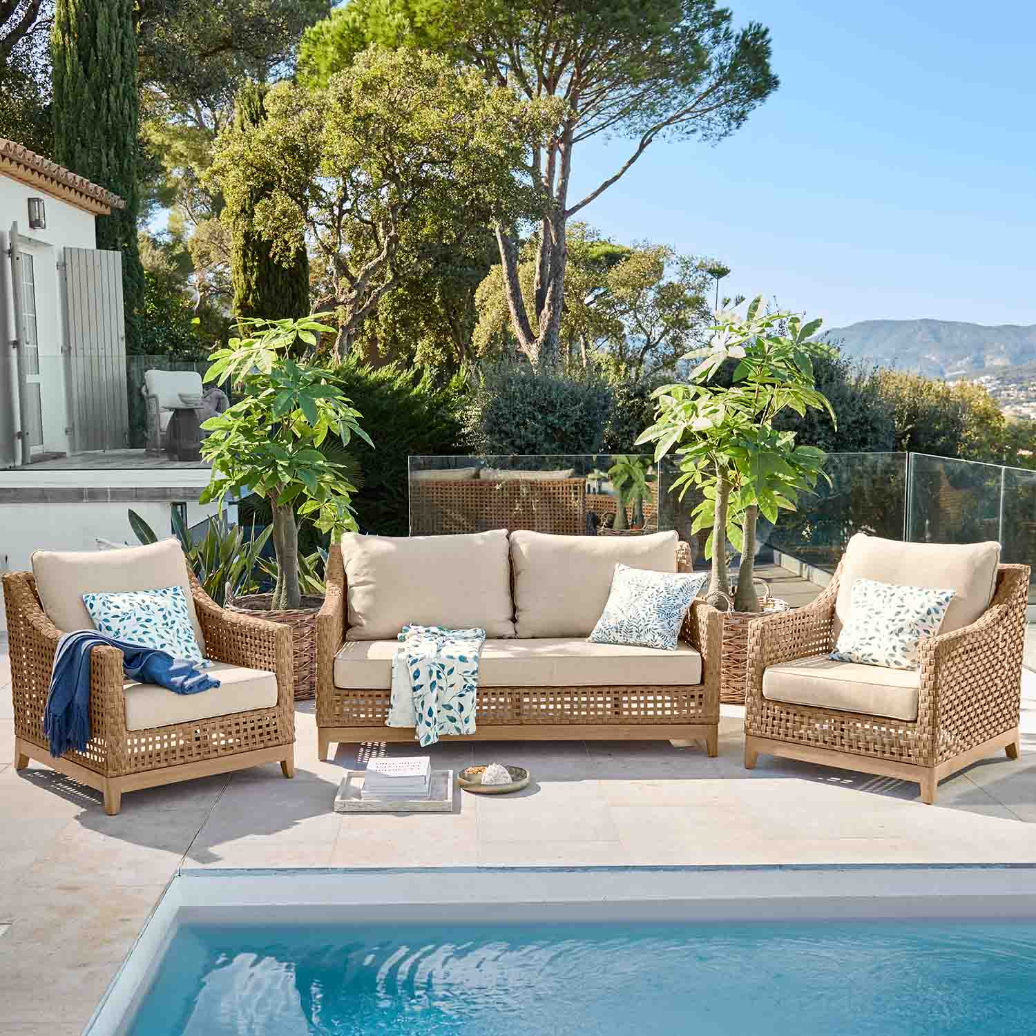 Conjunto de muebles de jardín de ratán natural con cojines beige junto a la piscina