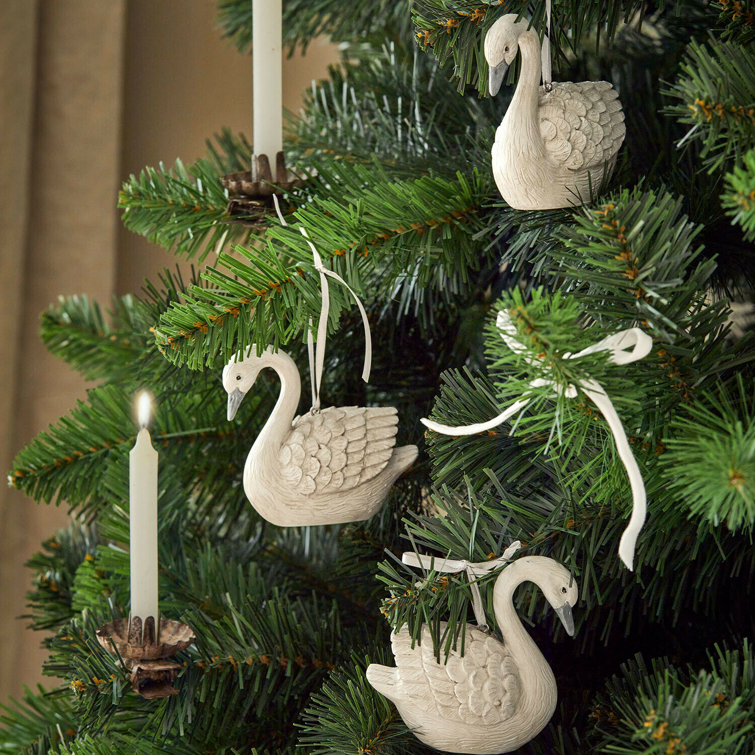 Set de 3 colgantes Elarin Adornos de cisnes blancos de madera colgados en árbol de Navidad verde con vela blanca encendida