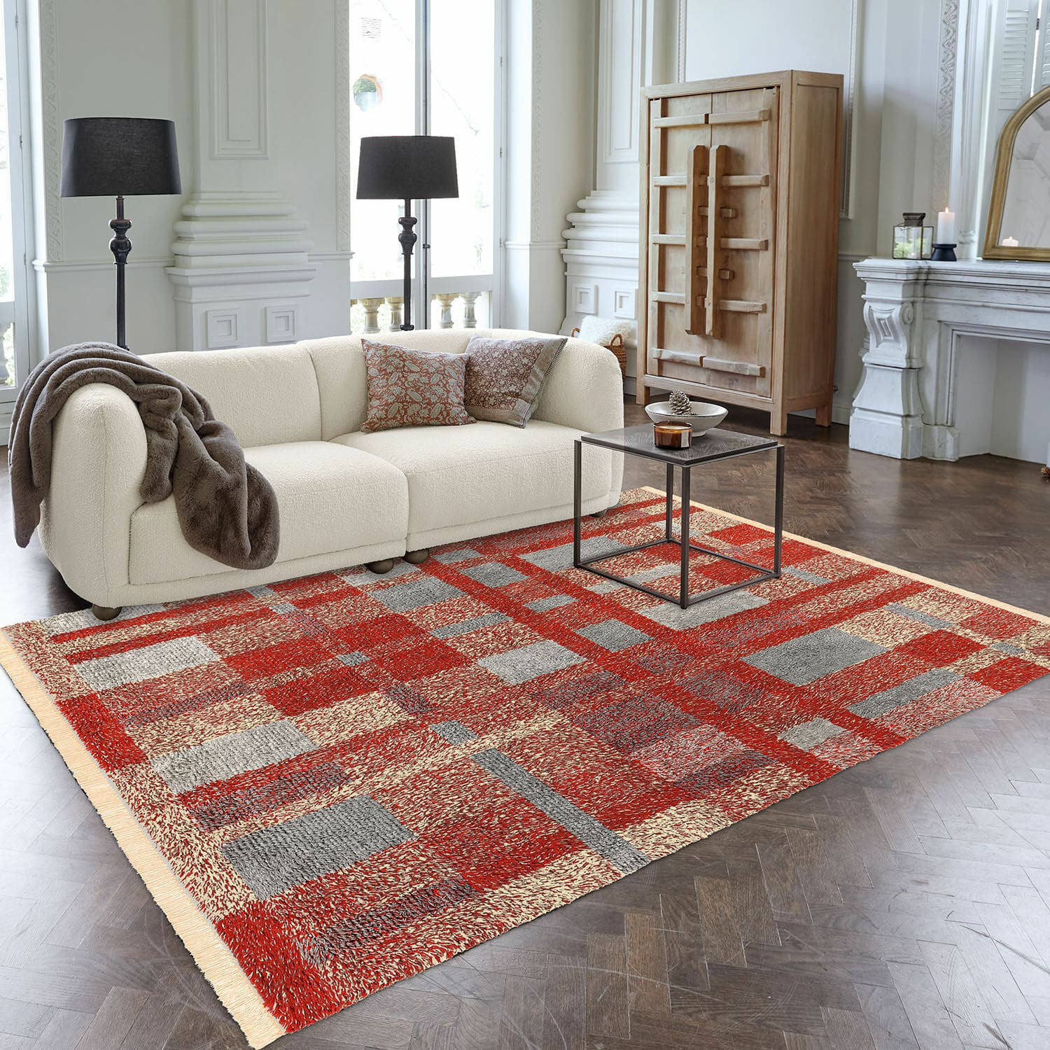 Alfombra Serenith Alfombra con diseño geométrico en rojo y gris sobre suelo de madera en sala moderna con sofá crema