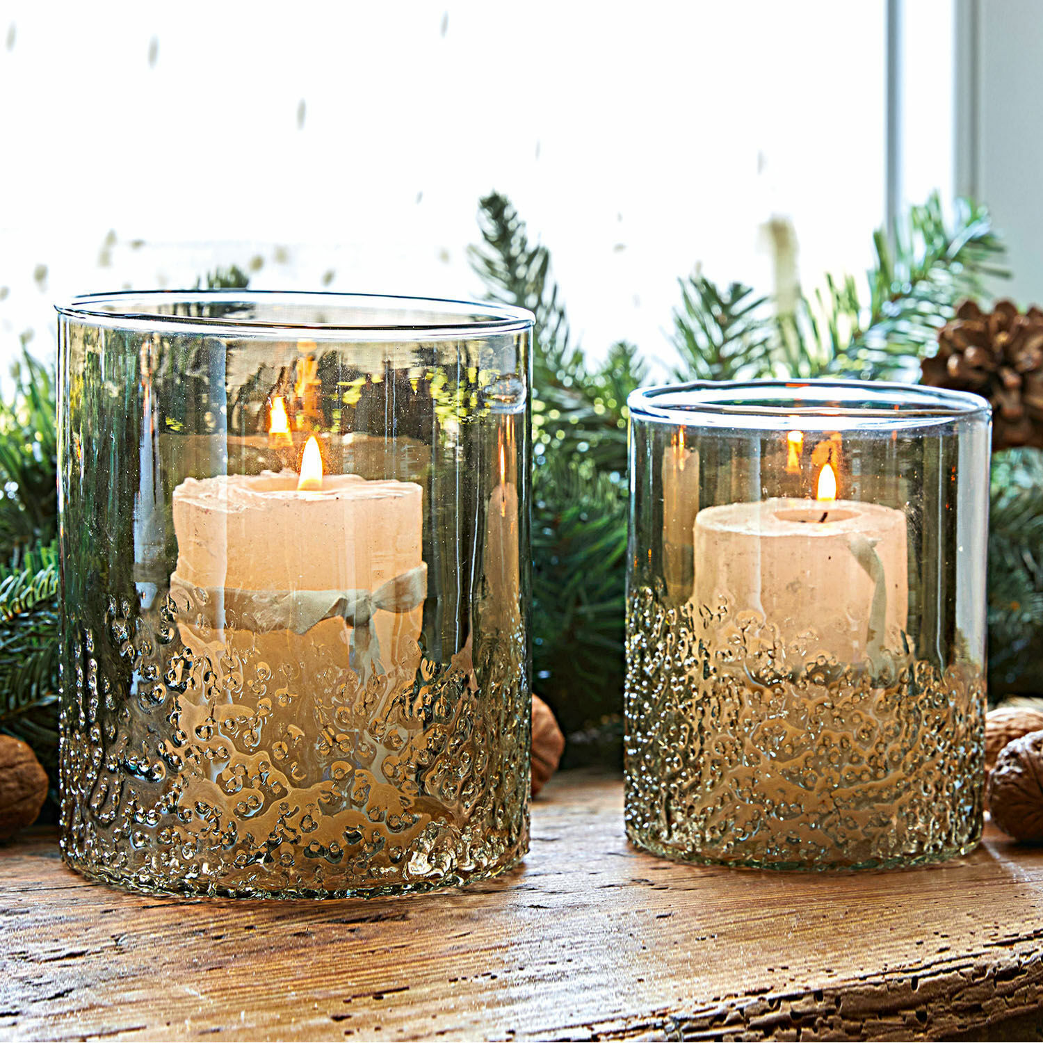 Set de 2 portavelas Plélo Portavelas de vidrio ahumado con textura y velas blancas sobre mesa de madera rústica