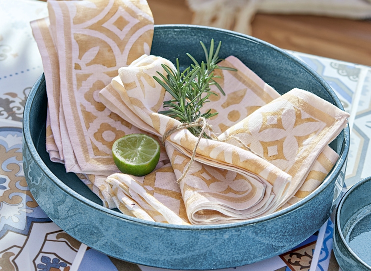 Cuenco de cerámica azul con servilletas de lino beige y blanco y rodaja de lima, estilo mediterráneo