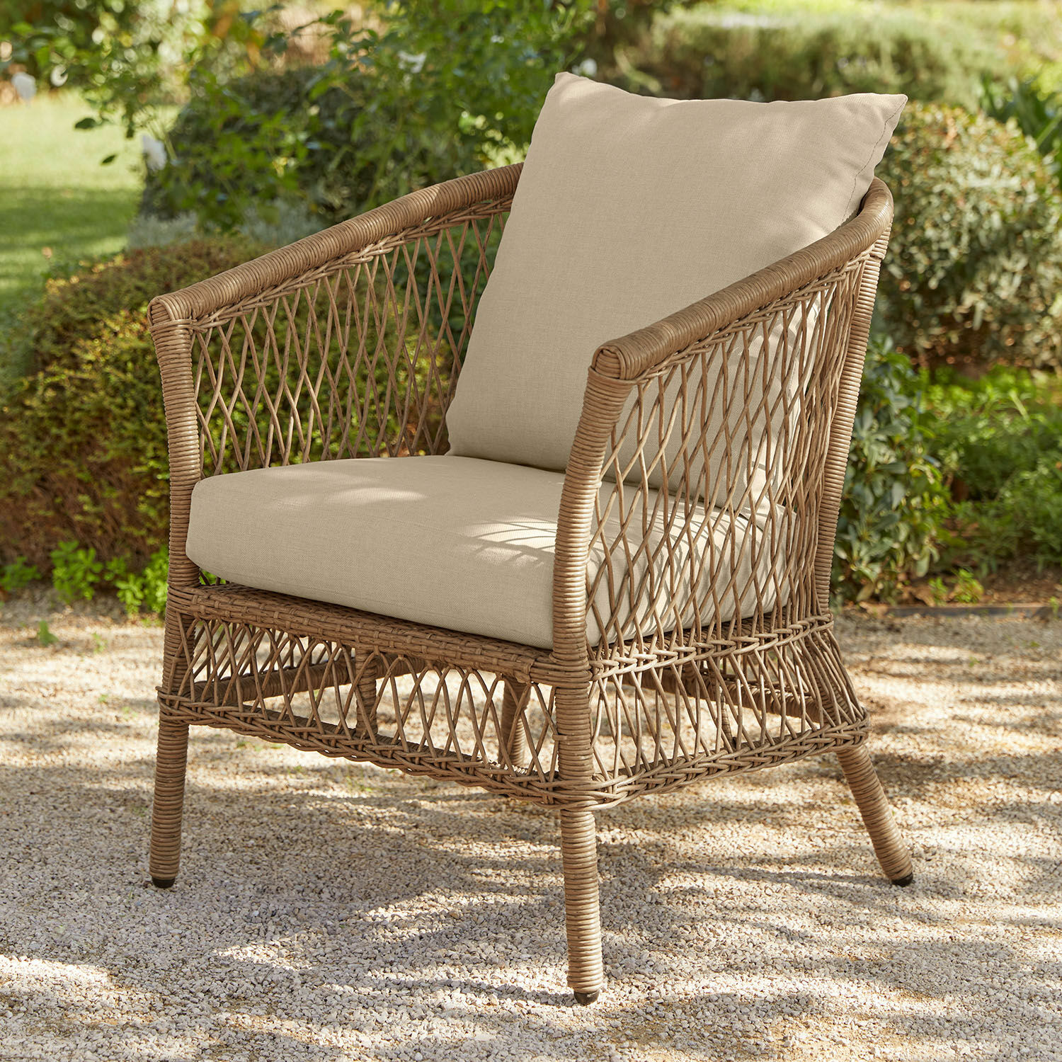 Sillón de jardín de ratán natural con cojines beige, ideal para relajarse al aire libre