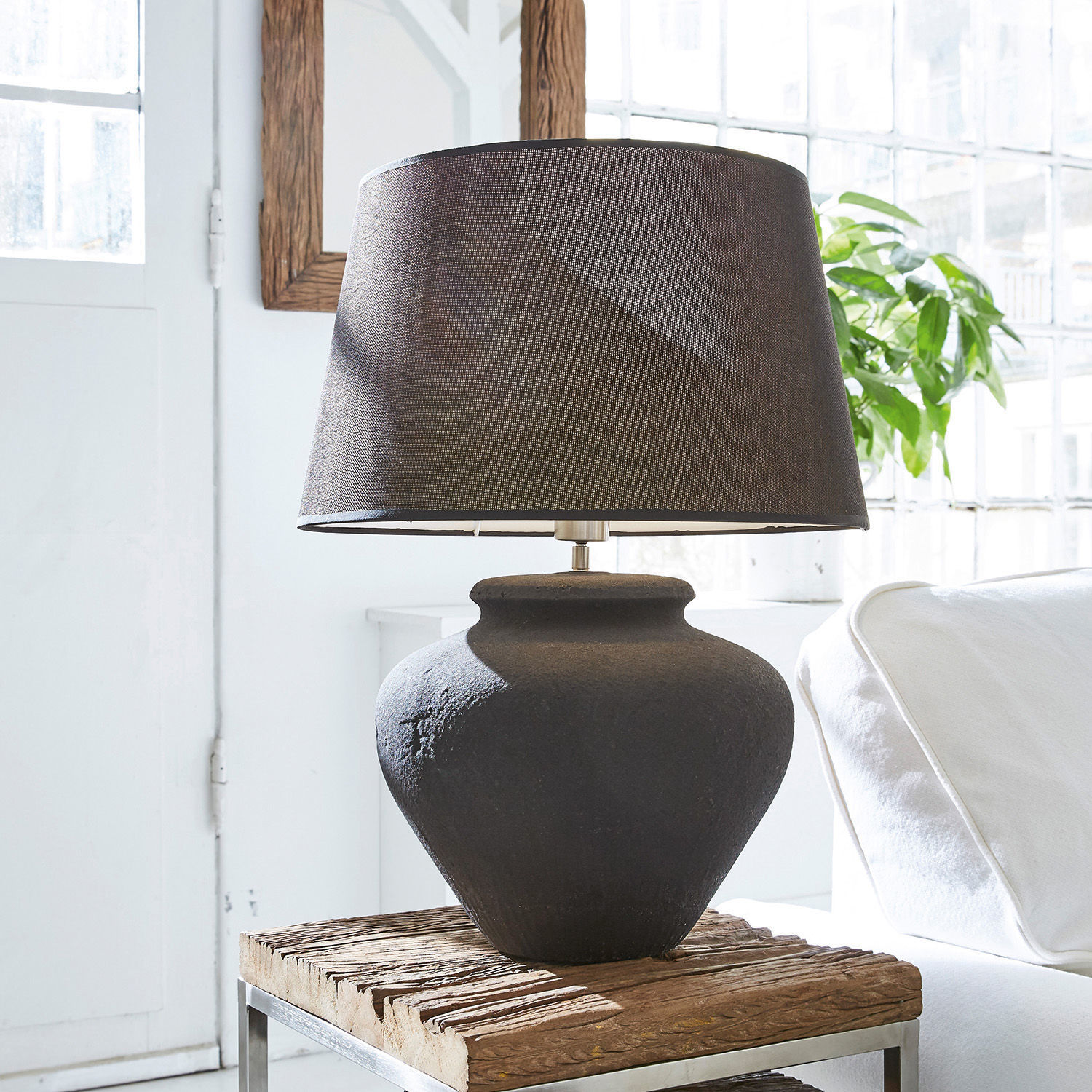 Lámpara de mesa Bandol Lámpara de mesa negra de cerámica con pantalla de tela sobre mesa de madera en interior luminoso