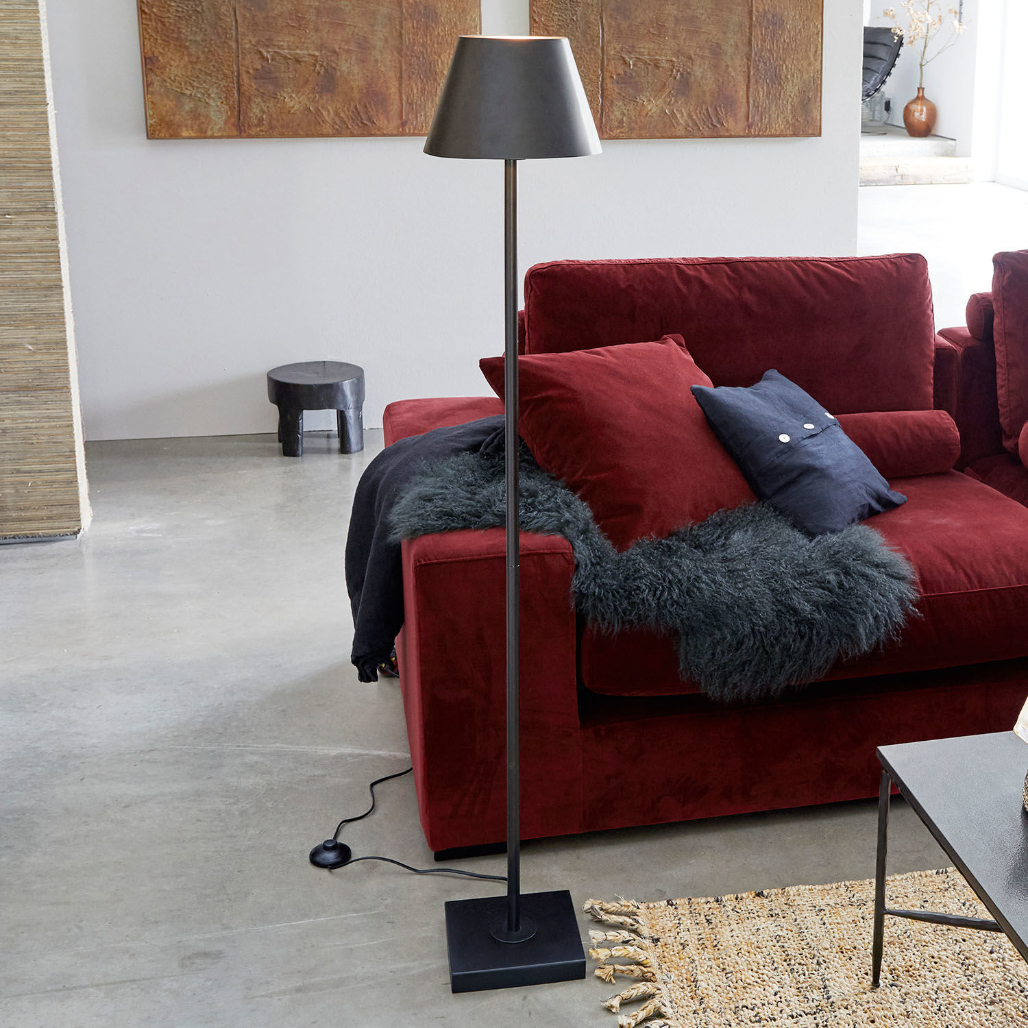 Lámpara de pie Marjan Lámpara de pie negra de metal con pantalla junto a un sofá rojo y alfombra en sala moderna