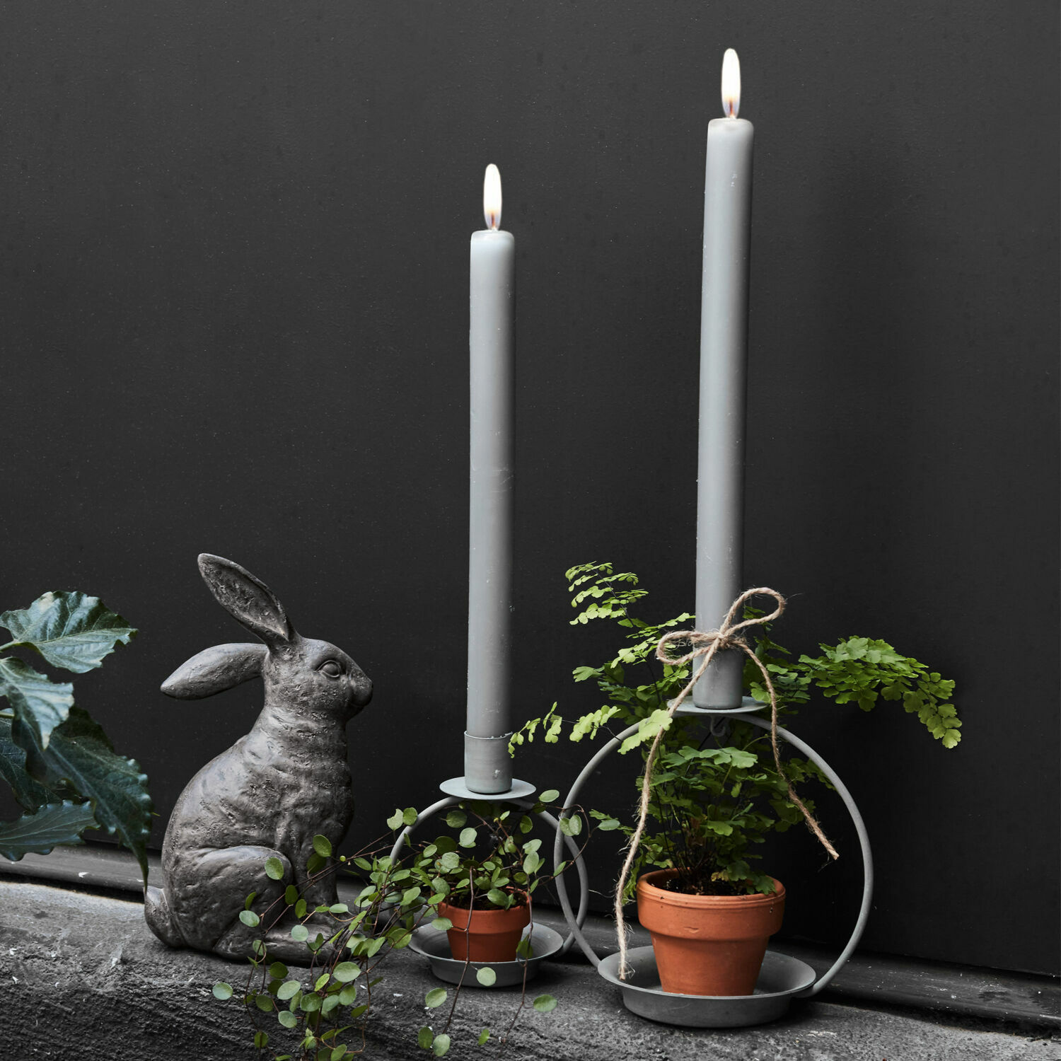 Set de 2 candeleros Nirrat Candelabros metálicos grises con velas grises, plantas verdes en macetas y decoración de conejo de piedra