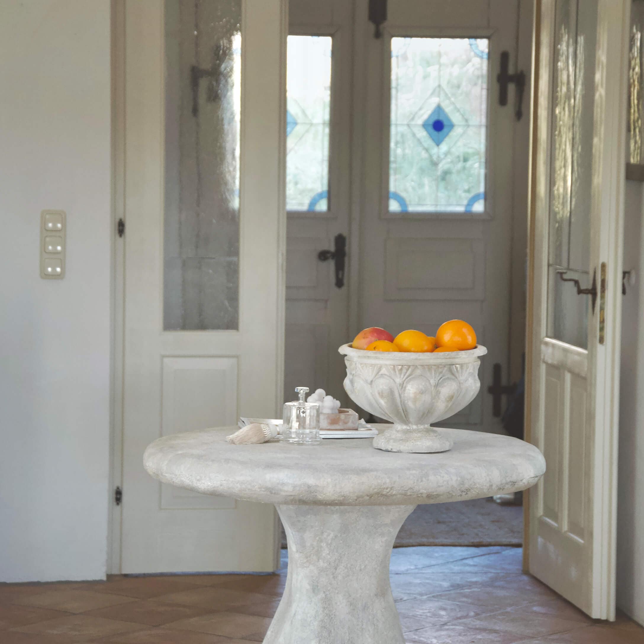 Mesa redonda de hormigón claro con cuenco decorativo vintage lleno de frutas naranjas