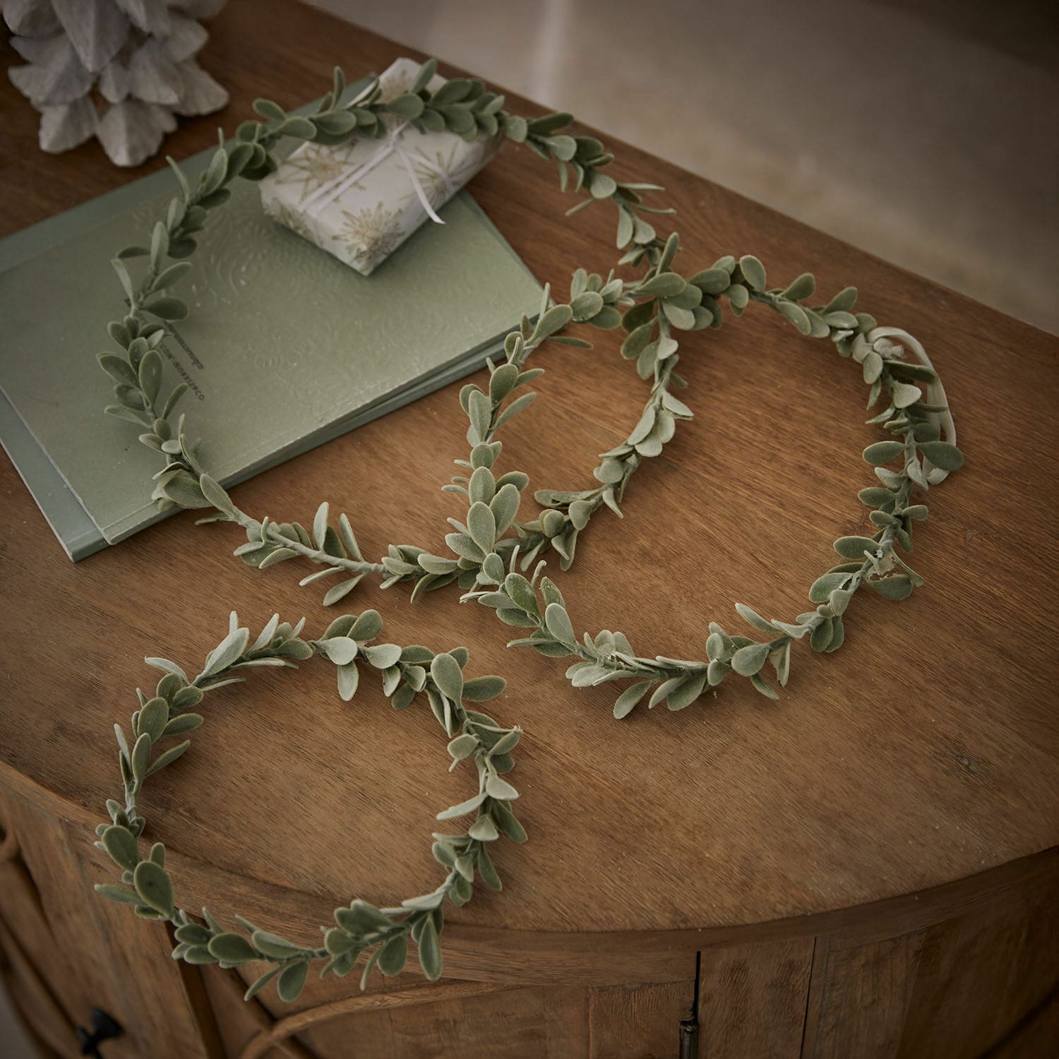 Set de 3 coronas Carivela Coronas decorativas verdes de hojas suaves sobre mesa de madera, adorno natural para interiores