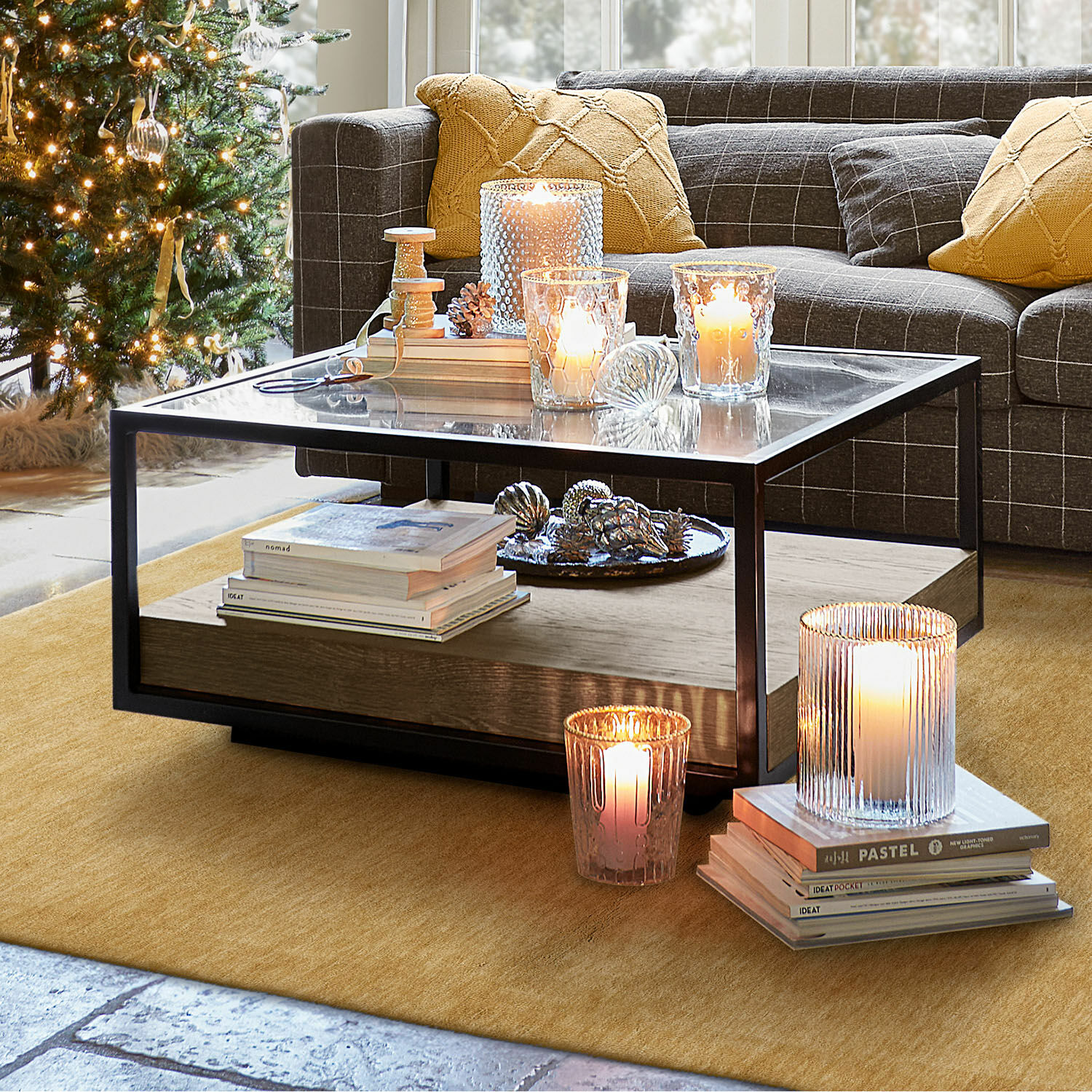Sala acogedora con sofá gris, cojines amarillos y árbol de Navidad iluminado con luces