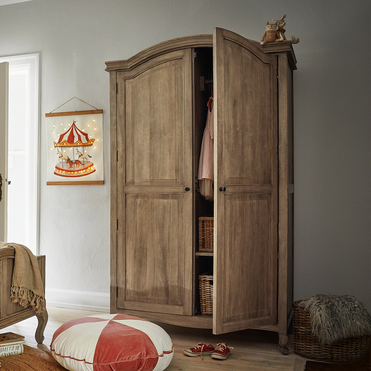 Armario Éveilou Armario de madera en color natural con puertas abiertas, cestas de mimbre y decoración en habitación infantil