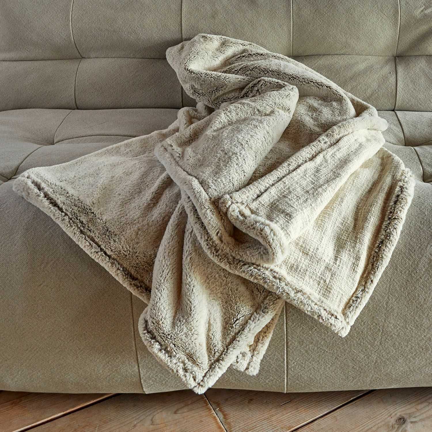 Plaid Newman Manta suave color crema con borde de piel sintética sobre sofá beige para ambiente acogedor