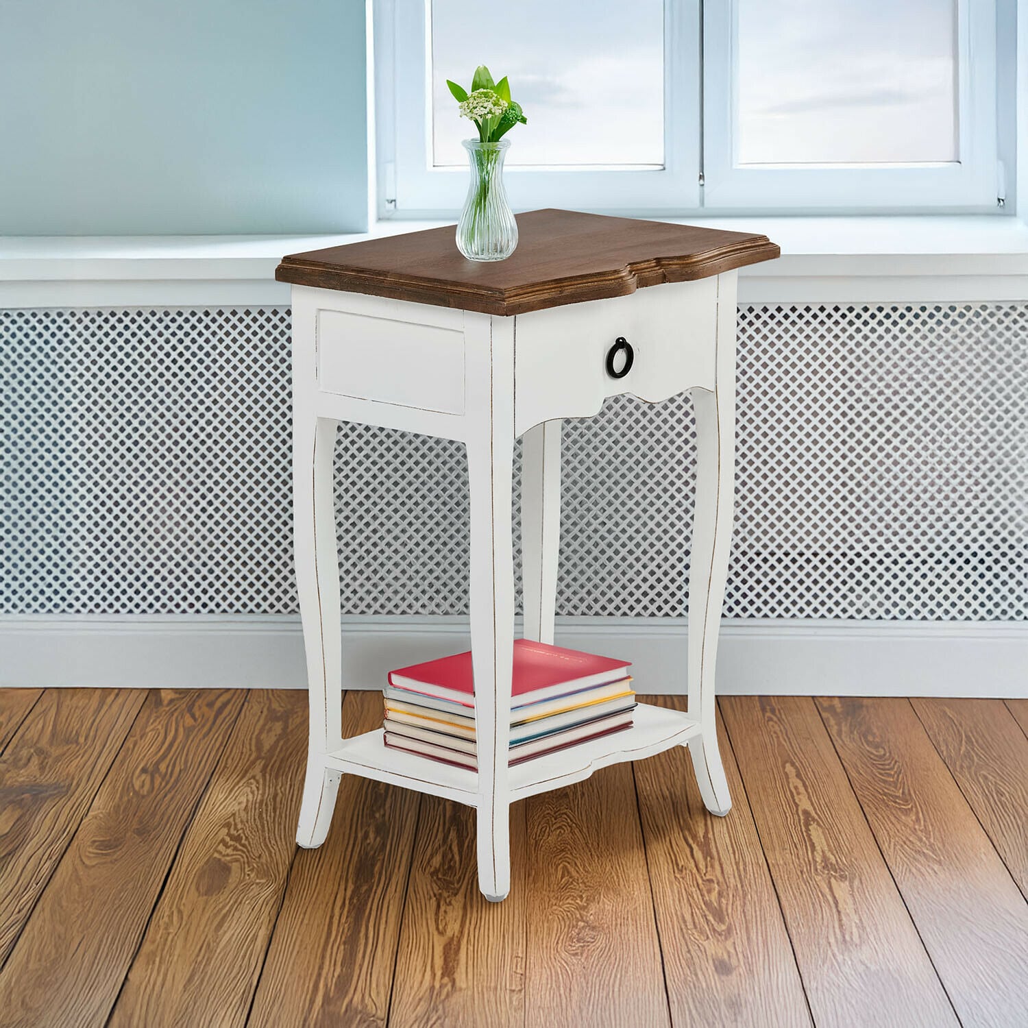 Mesa auxiliar Finstock Mesa auxiliar de madera blanca con cajón y tapa marrón, decorada con libros y jarrón con flores