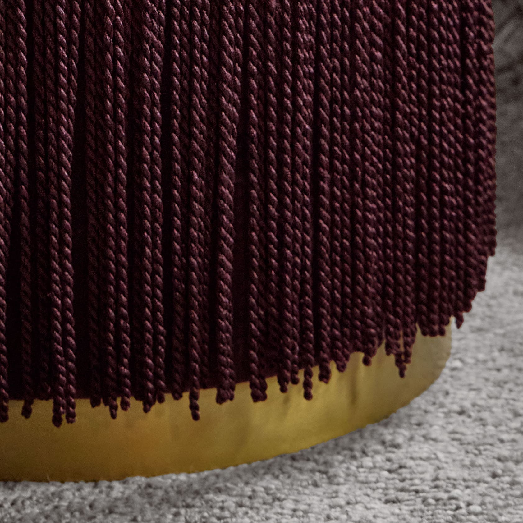Material trenzado burdeos sobre fondo amarillo sobre alfombra gris, textura textil decorativa