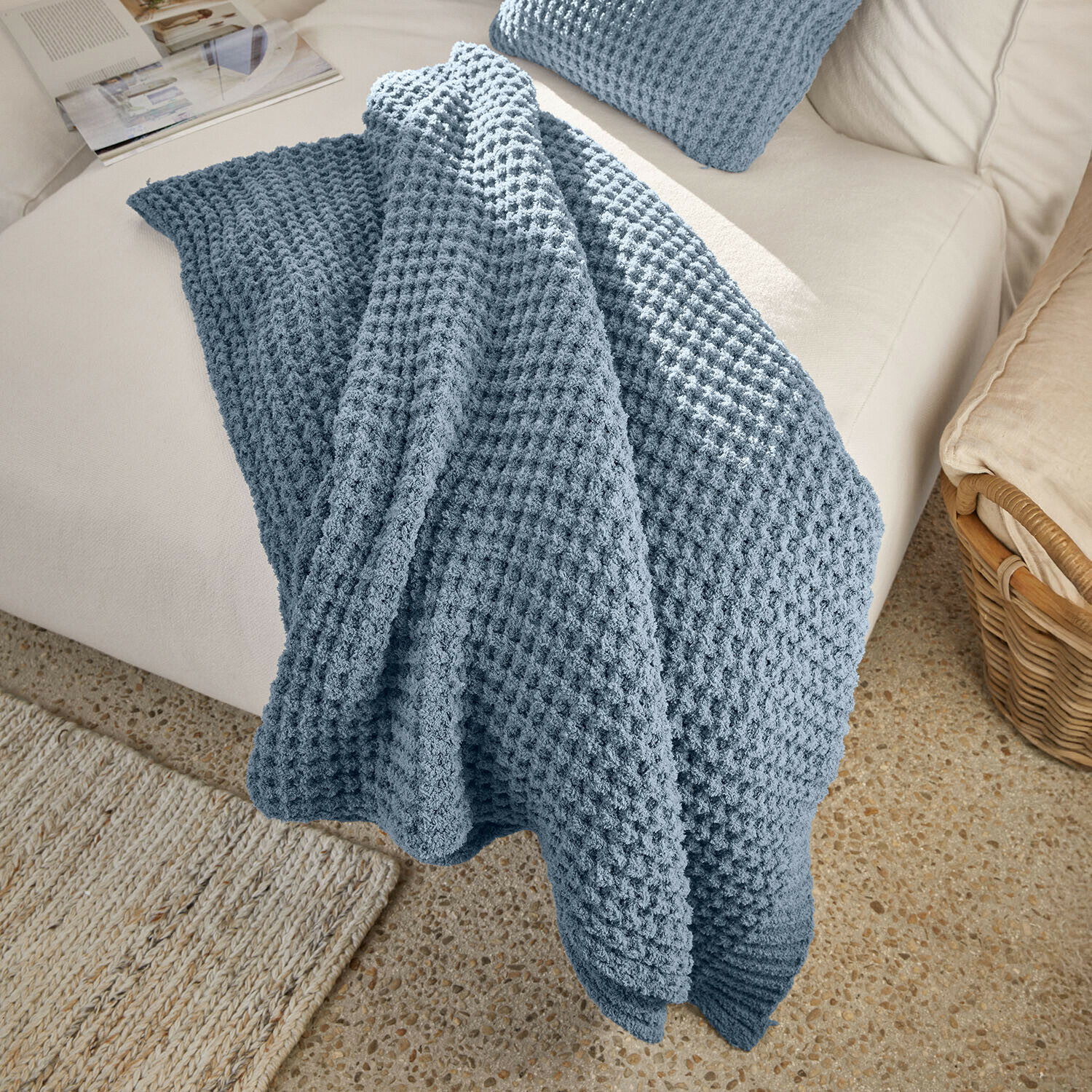 Manta azul con textura de gofre sobre sofá claro, cobija decorativa y acogedora para salón