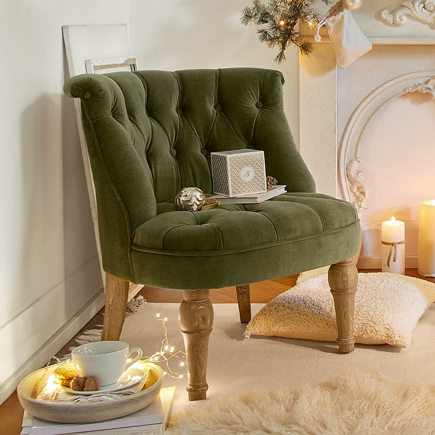 Sillón Ardilleux Sillón verde de terciopelo con patas de madera en interior acogedor con decoración navideña