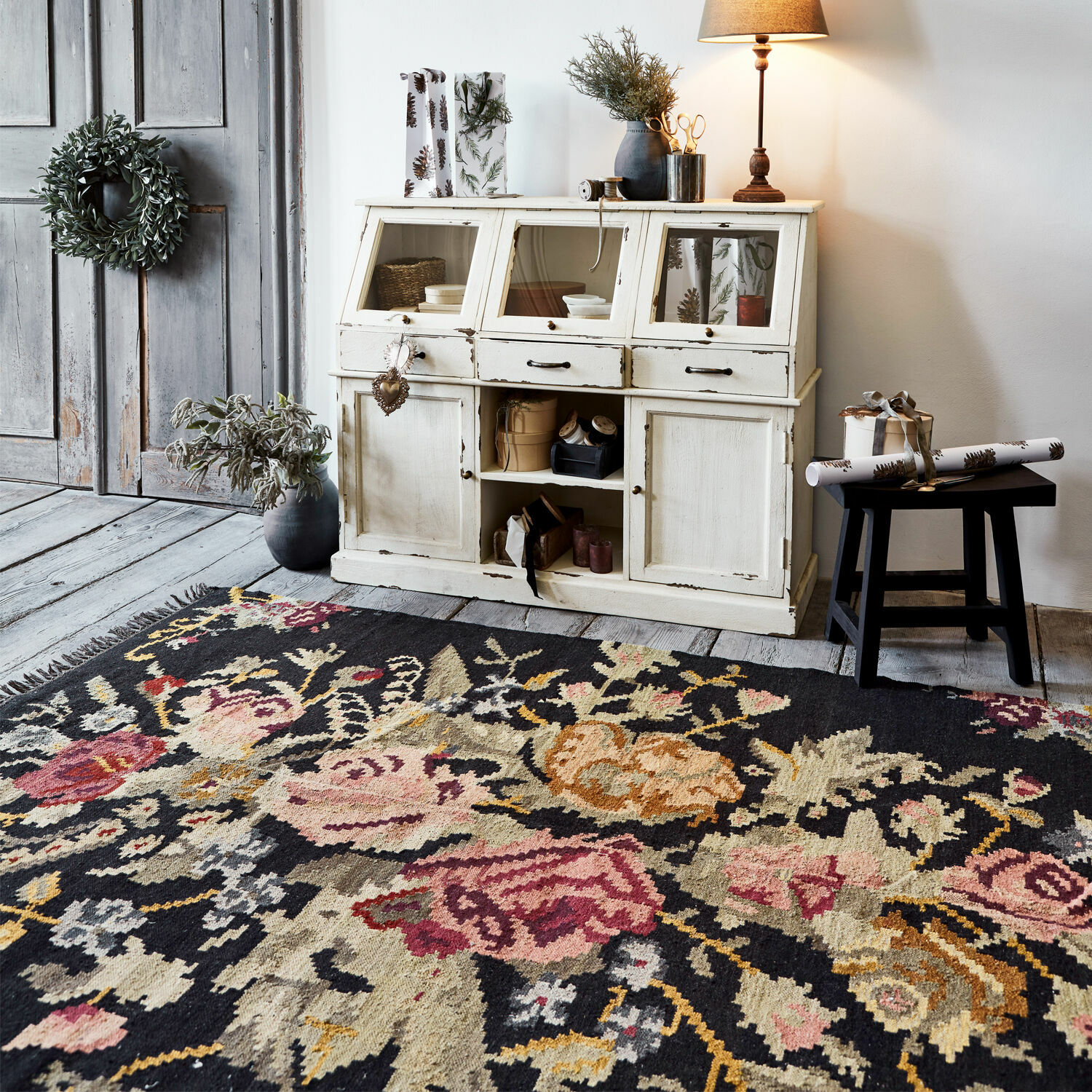 Alfombra Matteo Alfombra con diseño floral oscuro frente a aparador blanco de madera y suelo gris de madera