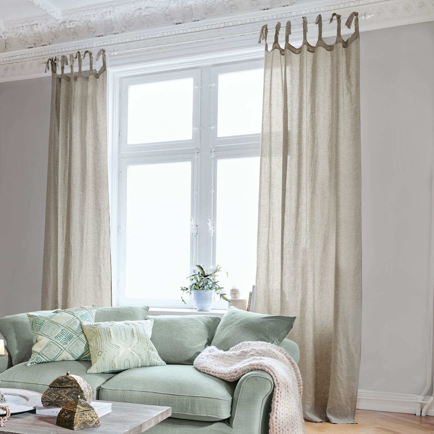 Cortina Monthelie Cortinas de lino beige en ventana de sala luminosa con sofá verde y cojines decorativos