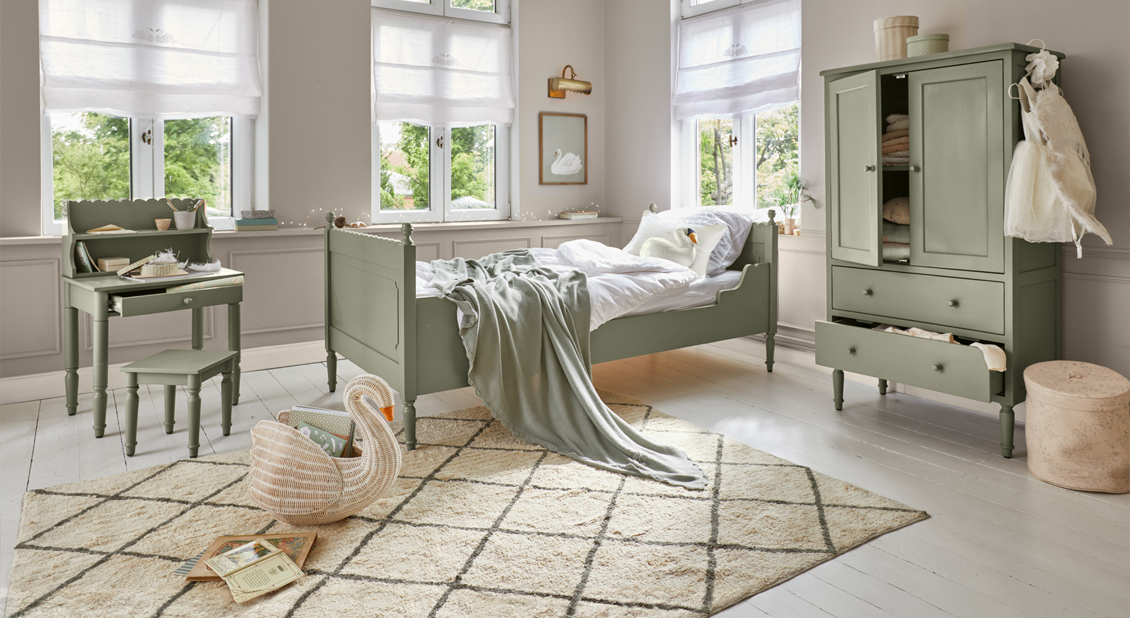 Muebles infantiles de madera color verde menta con cama, escritorio y armario en habitación luminosa y acogedora