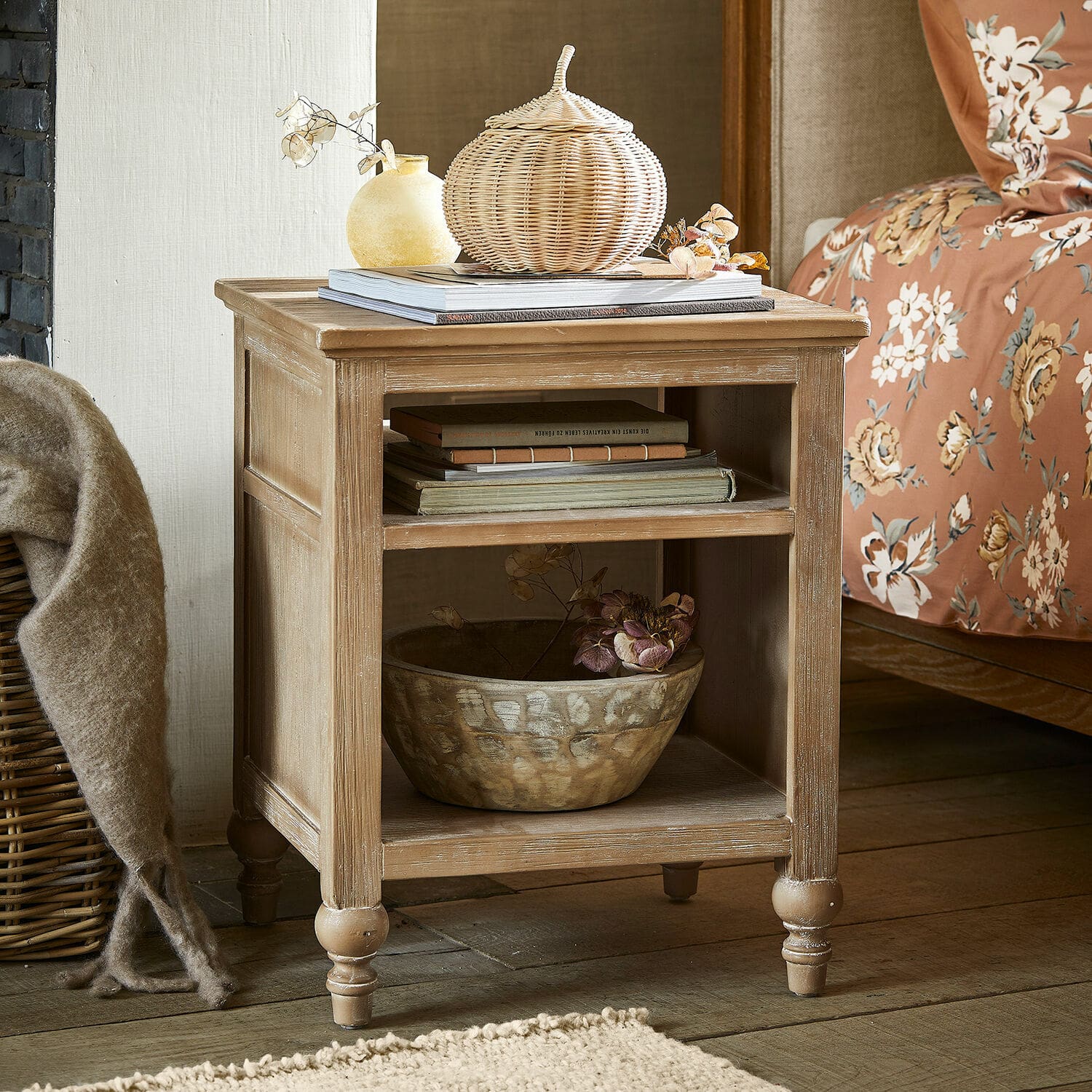 Mesita de noche de madera color natural con estantes y decoraciones en dormitorio