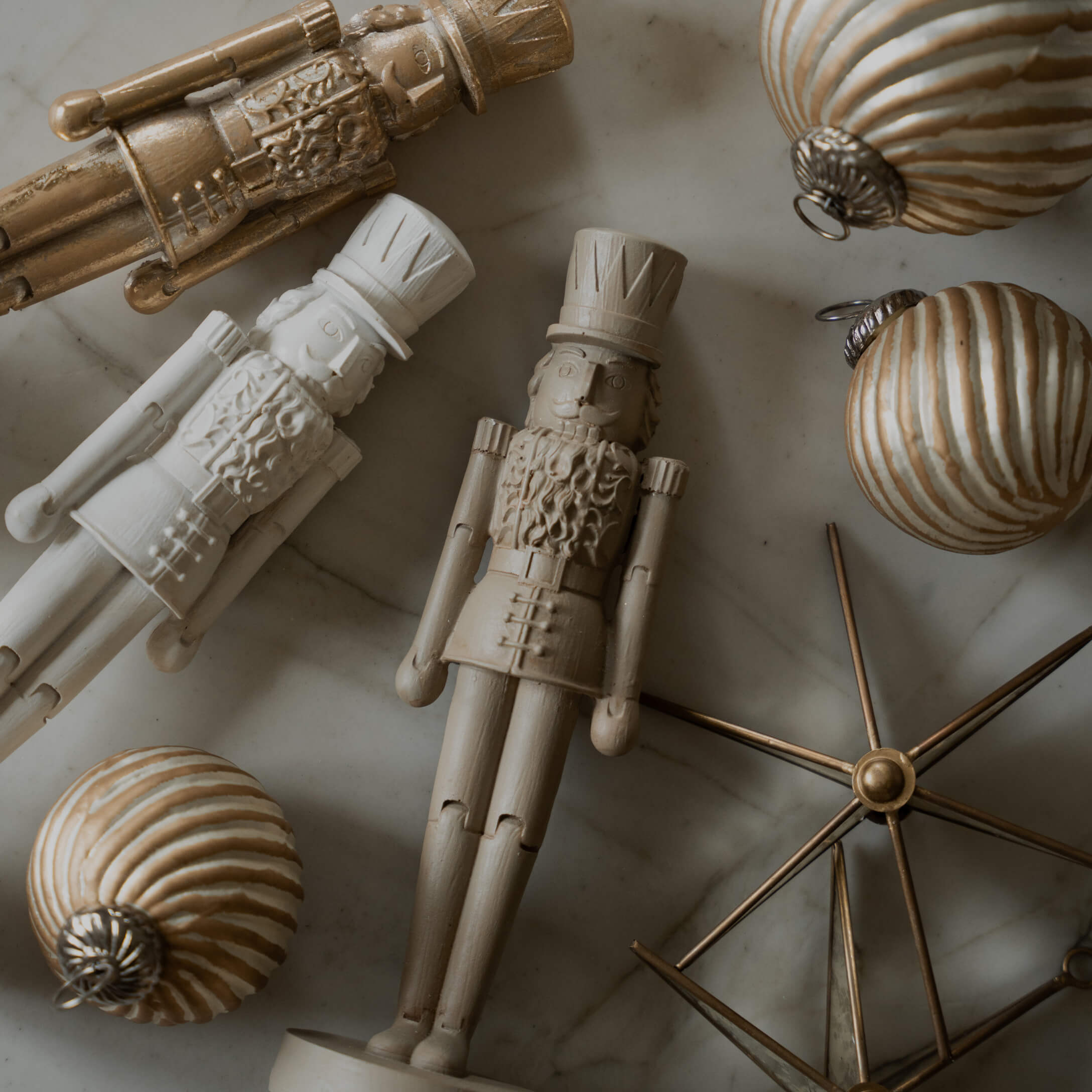 Figuras de madera de soldados y bolas navideñas doradas sobre fondo de mármol, decoración festiva