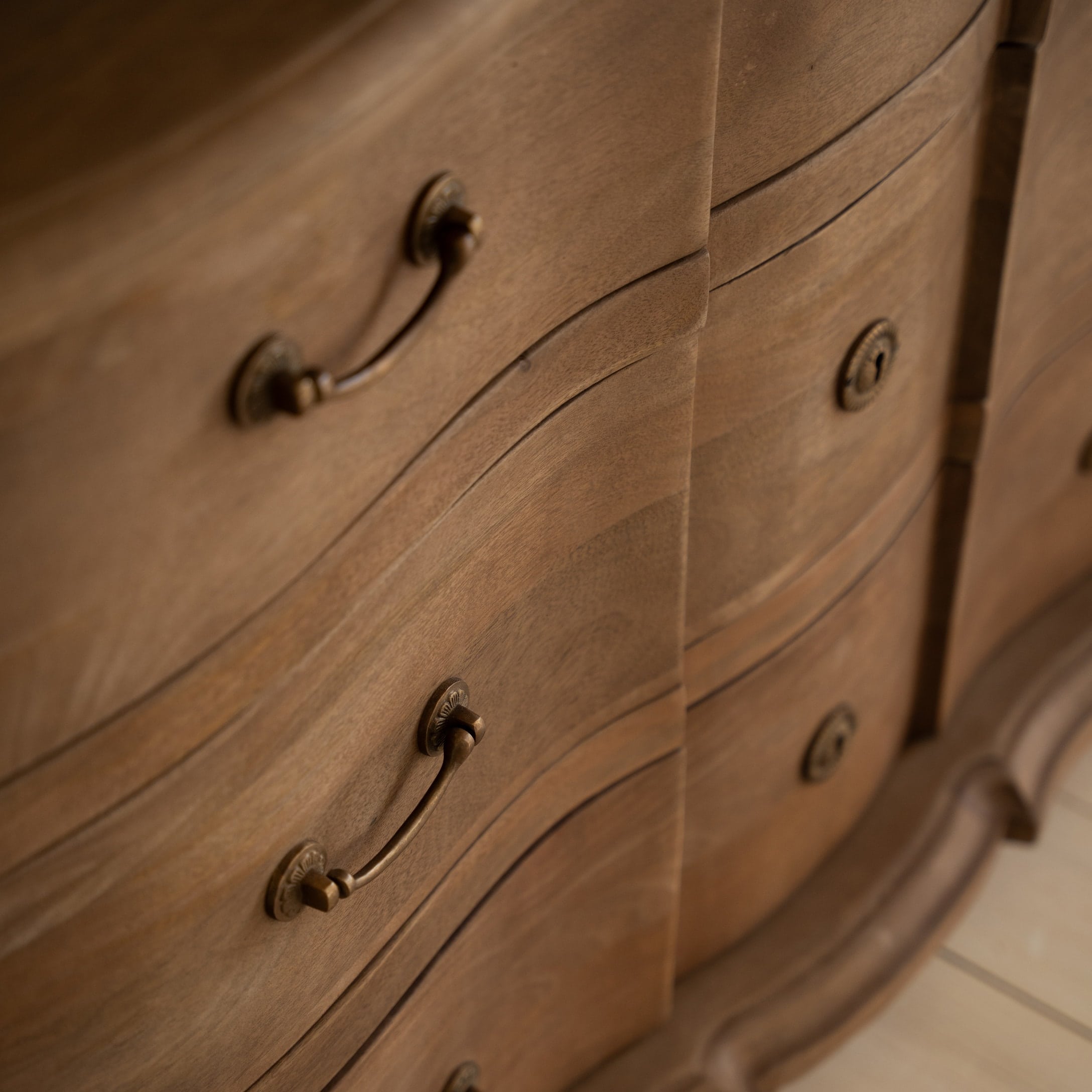 Primer plano de cómoda de madera con tiradores decorativos de latón y acabado natural de la madera