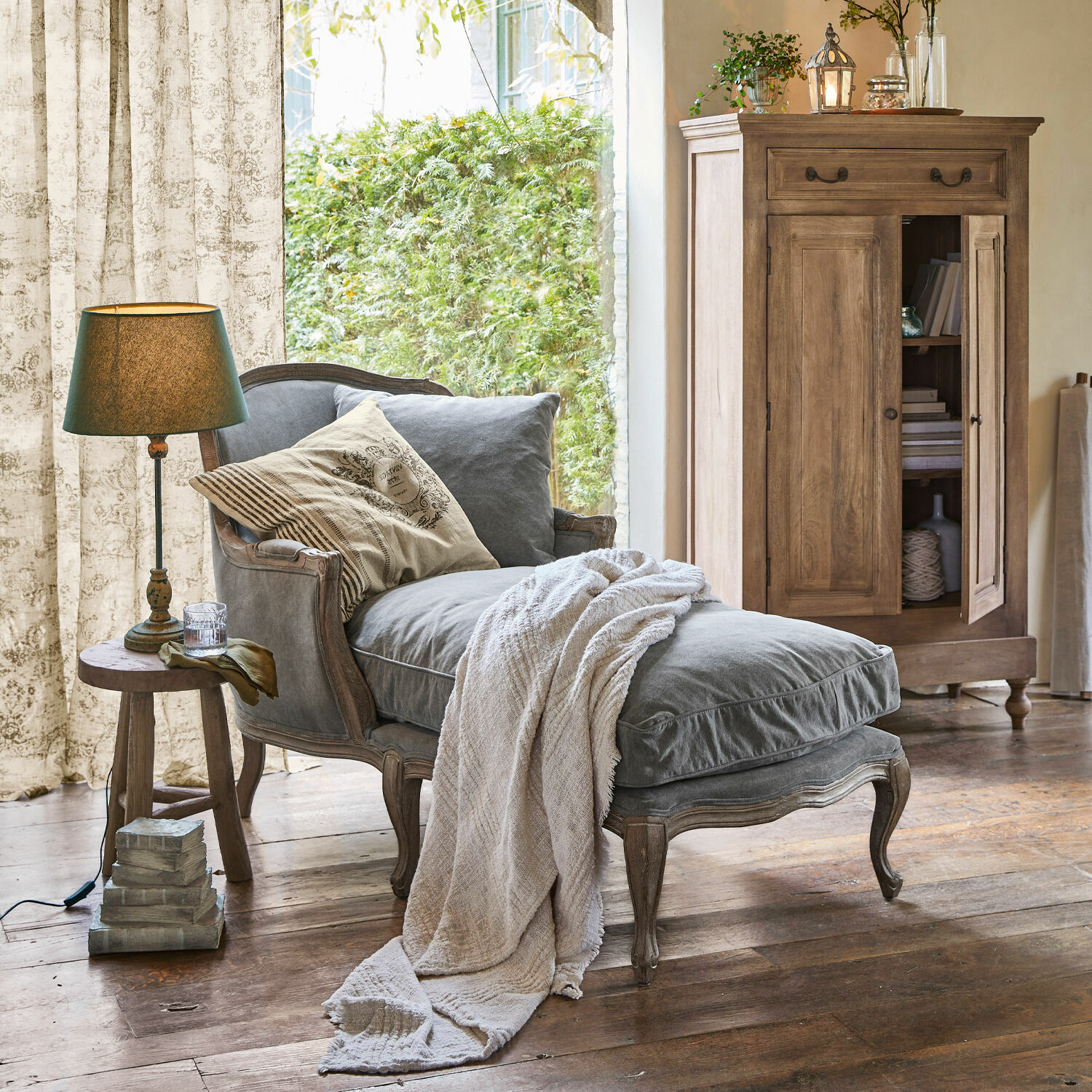 Chaise longue Muel Tumbona tapizada gris con marco de madera y manta beige en sala de estilo rústico