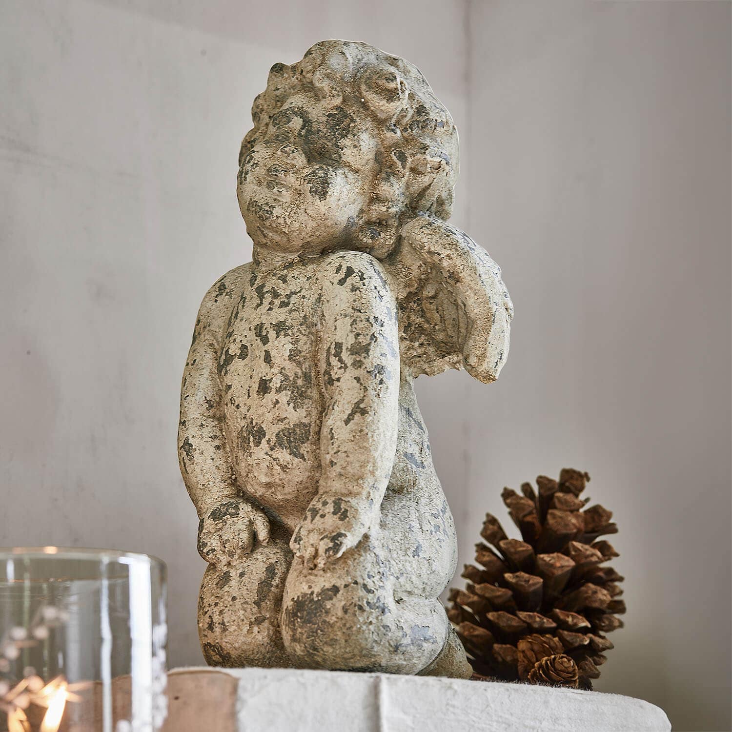 Figura de ángel de piedra envejecida en beige, decoración interior con piña natural
