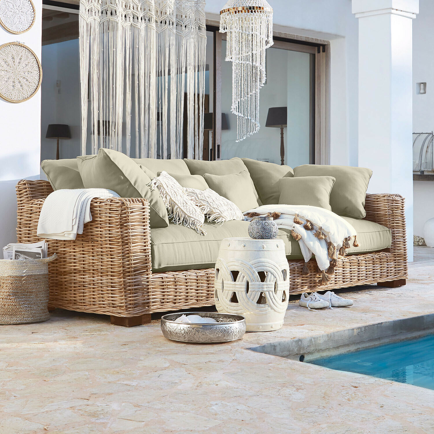 Sofa Rimini Sofá de ratán con cojines beige y decoración bohemia junto a la piscina