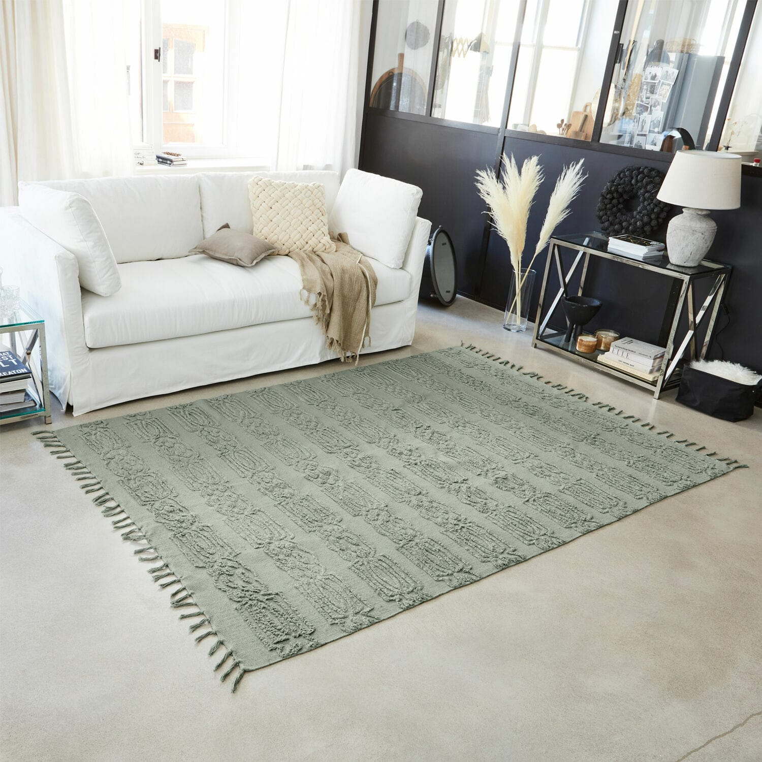 Alfombra decorativa verde con flecos sobre suelo claro en salón moderno y luminoso