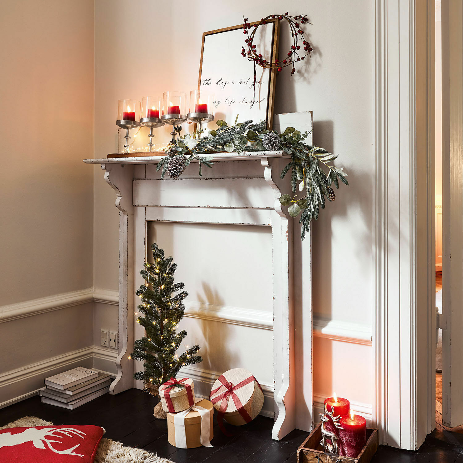 Consola de chimenea Cessieu Chimenea decorativa blanca de madera con guirnalda verde, velas rojas y regalos navideños