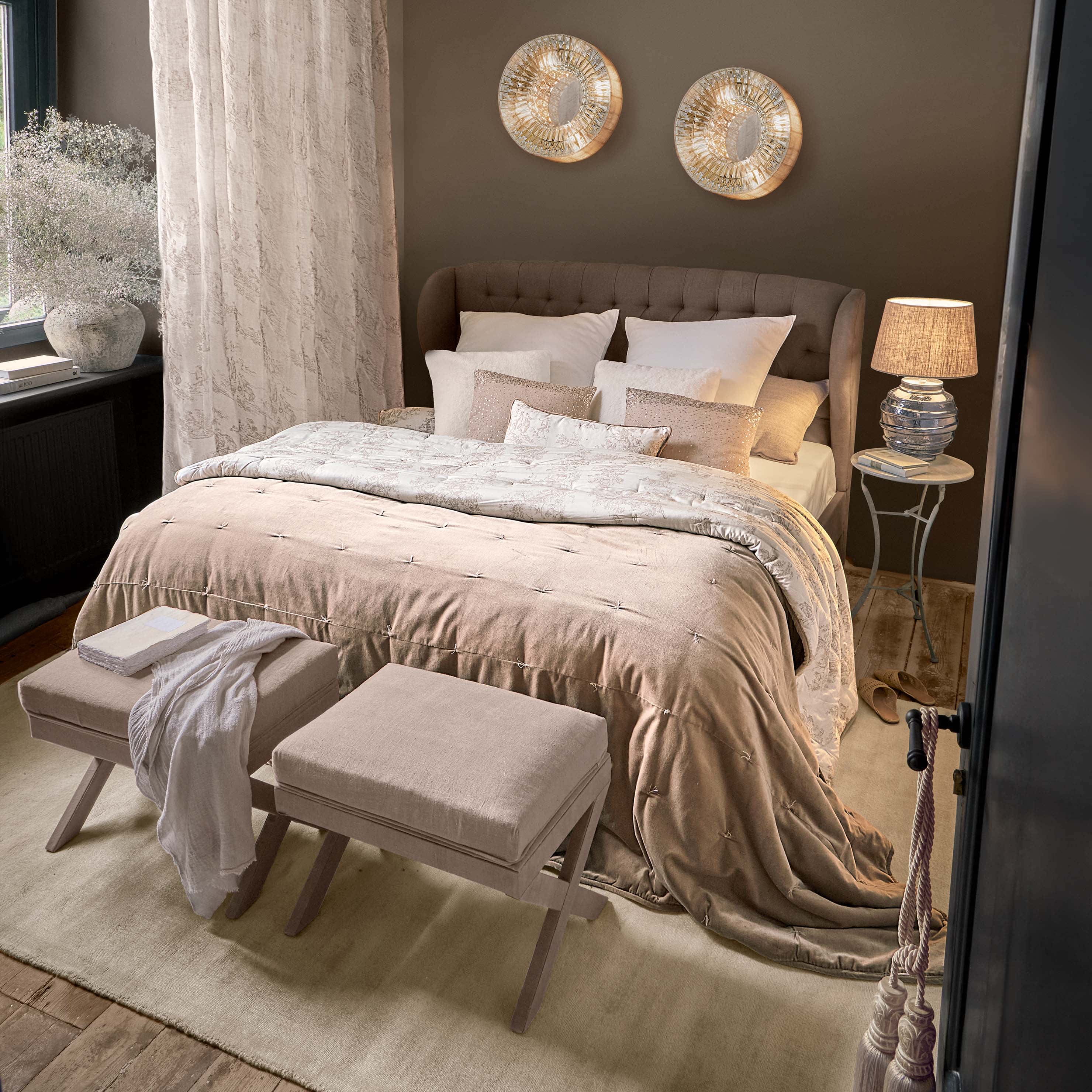 Dormitorio acogedor con cama tapizada marrón y ropa de cama beige con cojines decorativos
