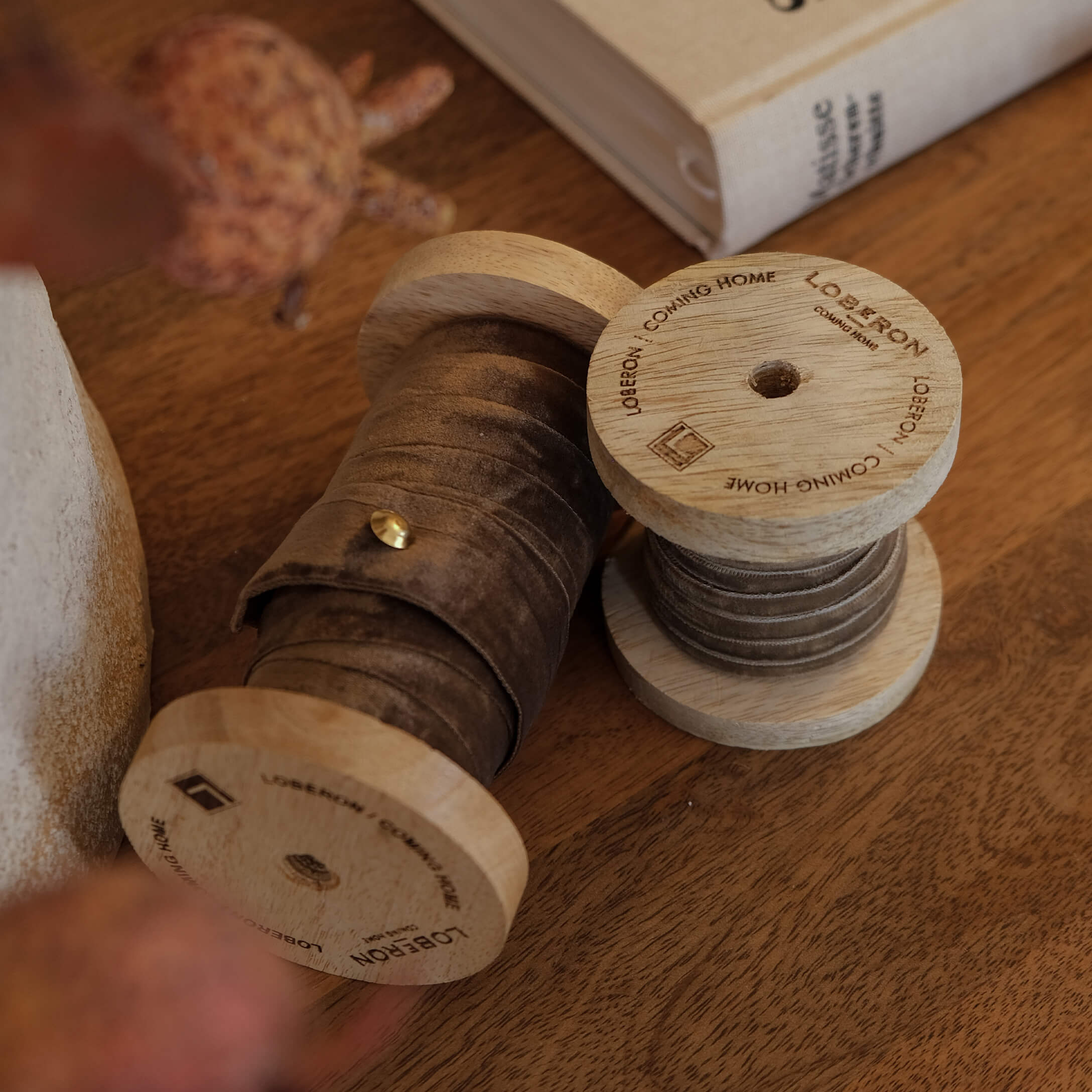 Carretes de madera con cinta de terciopelo marrón sobre mesa de madera, decoración interior