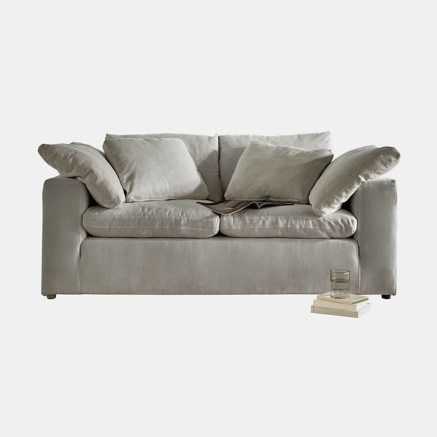 Sofá beige de tela suave con cojines y libros al lado, mueble cómodo para salón