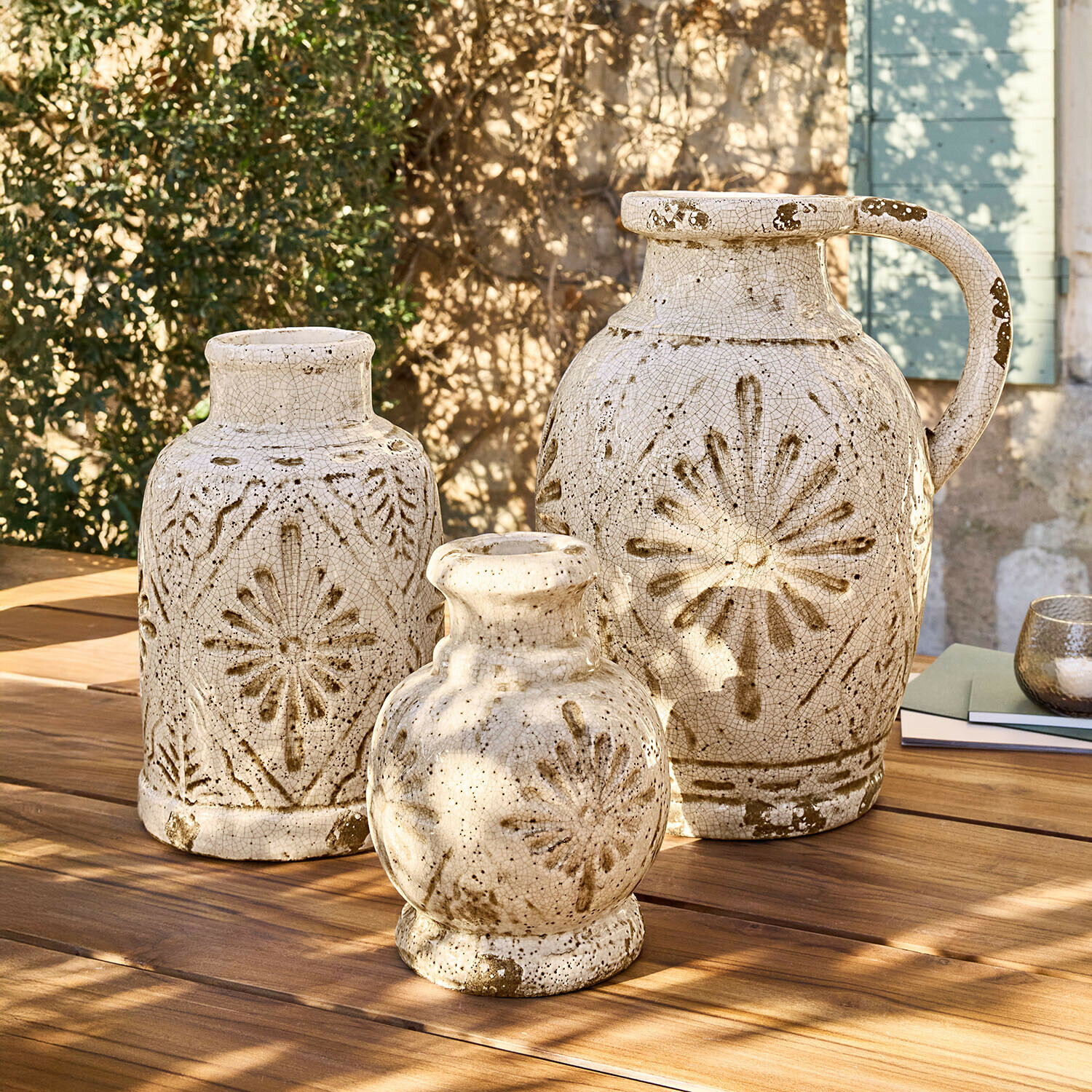 Set de 3 jarrones Orsémine Conjunto de tres jarrones de cerámica crema con motivos marrones sobre mesa de madera al aire libre