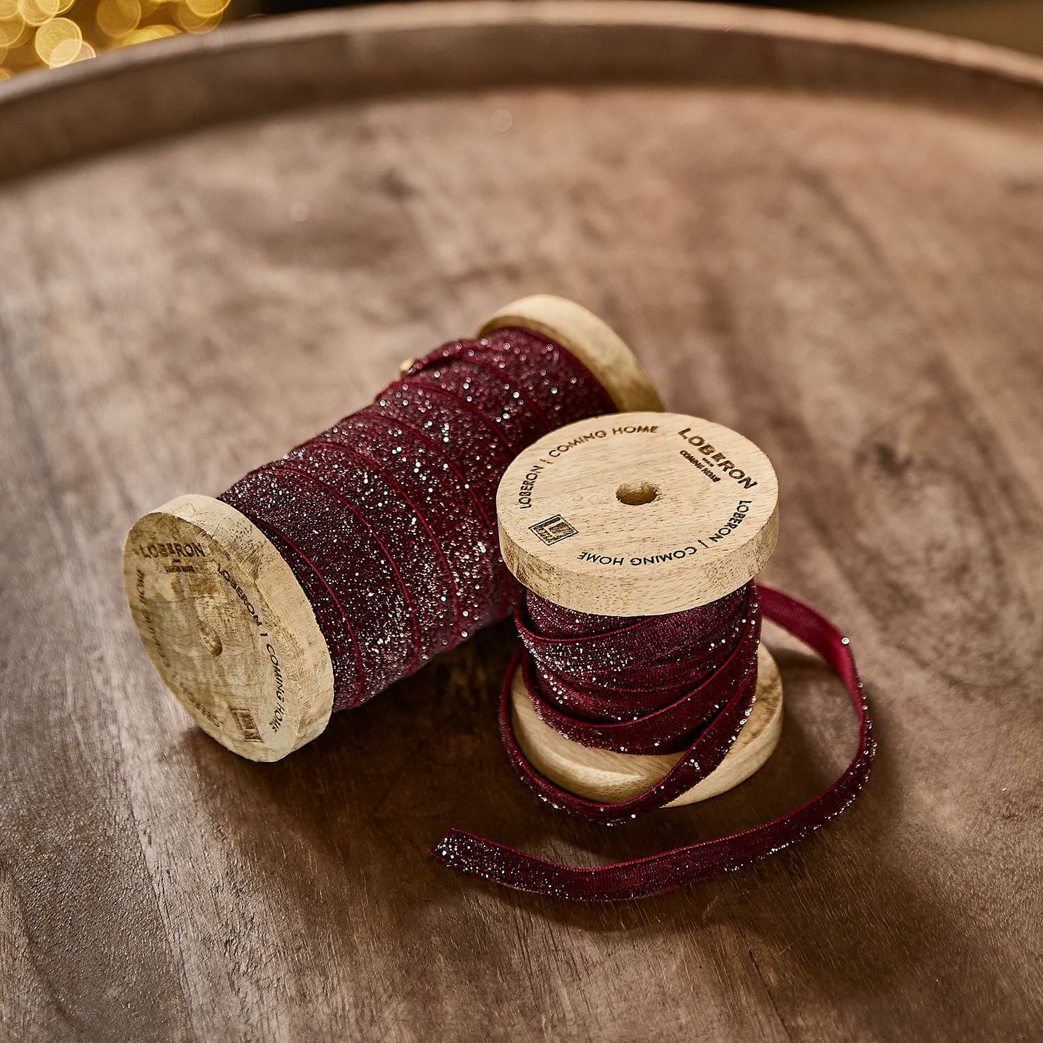 Set de 2 cintas de terciopelo Risorio Cinta burdeos con purpurina en carretes de madera sobre mesa de madera para decoración y manualidades