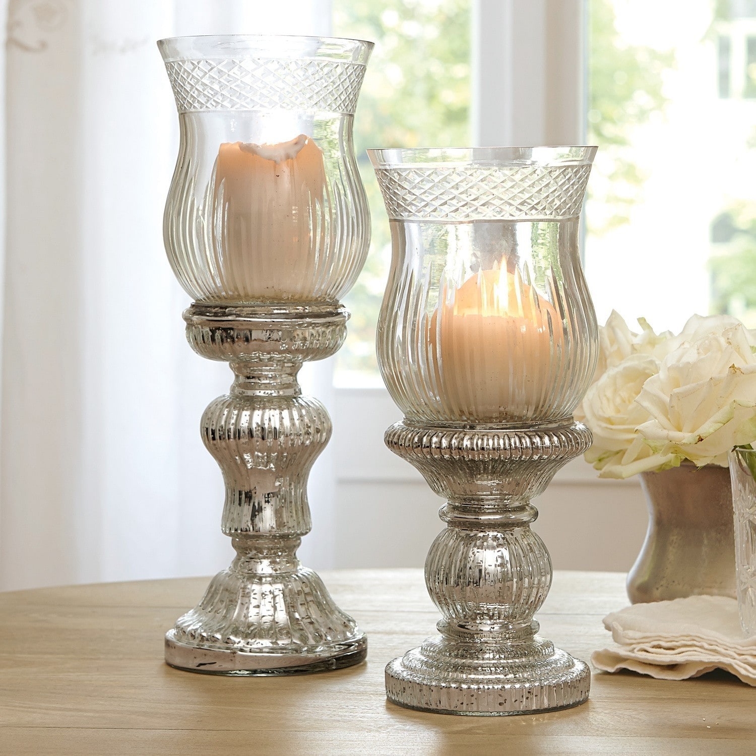 Set de 2 candeleros Luisant Dos candelabros decorativos de vidrio con efecto plata envejecida sobre mesa de madera en interior luminoso