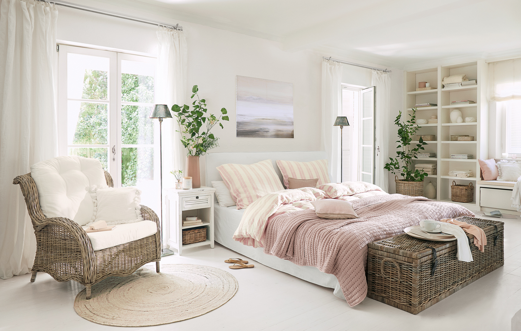 Dormitorio acogedor estilo rústico con sillón de mimbre y colcha rosa en la cama