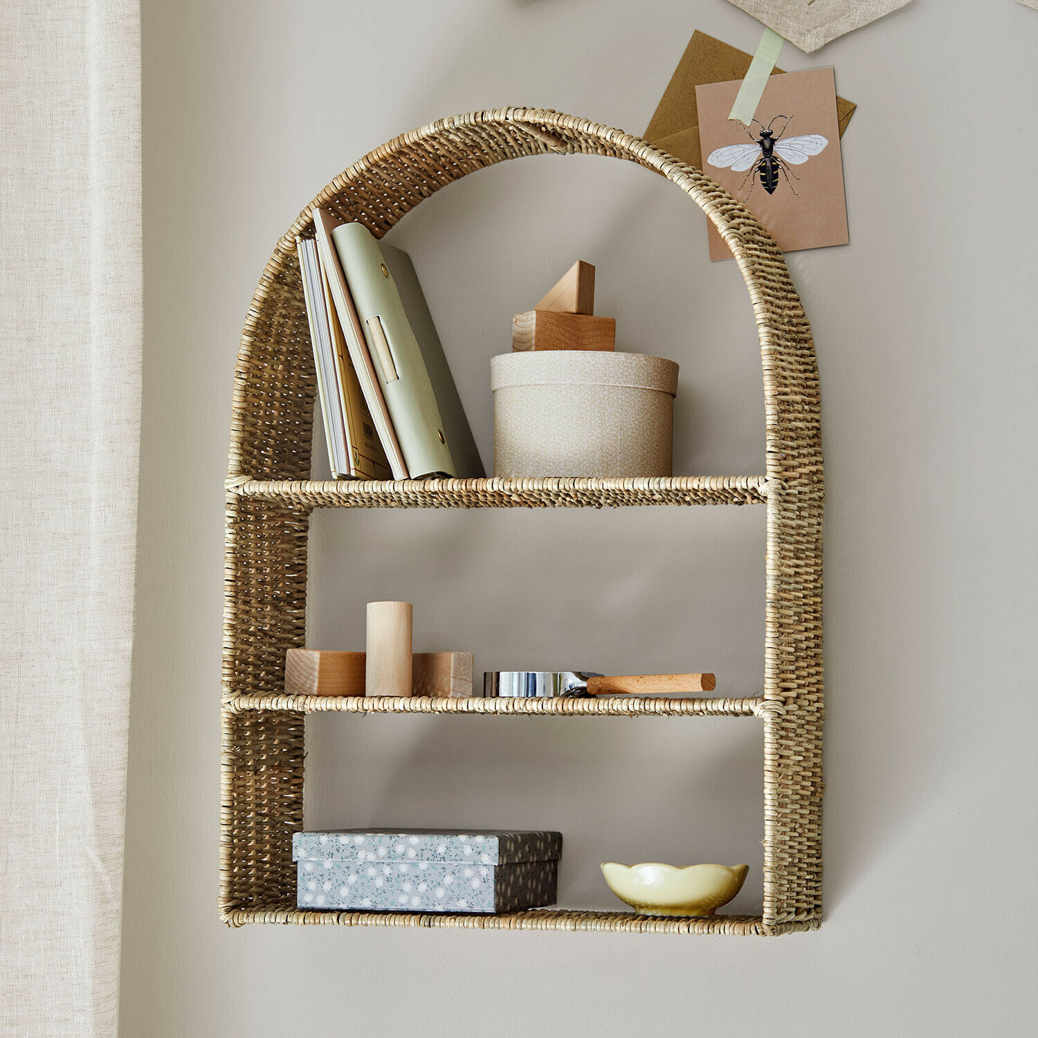 Estantería de pared de ratán natural con decoraciones y libros para almacenamiento