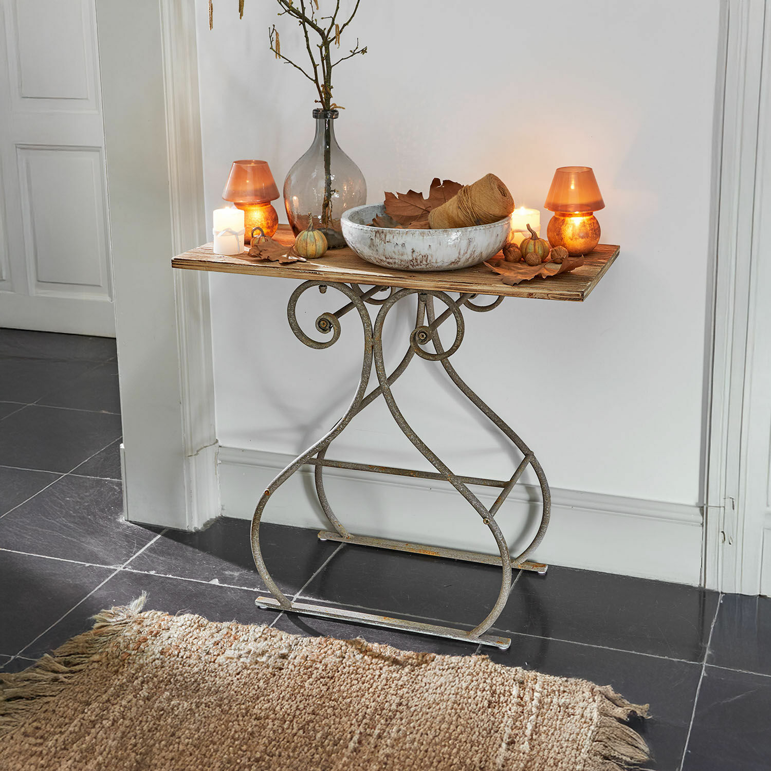 Mesa con base metálica y tablero de madera decorada con velas y jarrón vintage