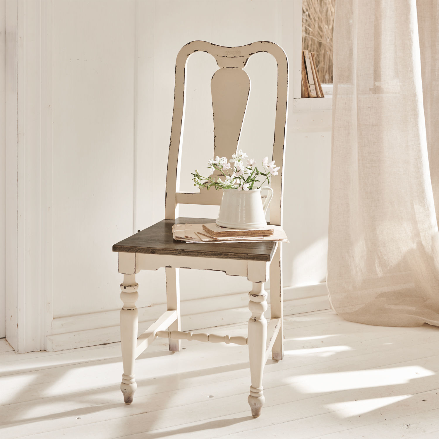 Silla Harry Silla vintage de madera blanca con asiento oscuro y jarra con flores en habitación luminosa