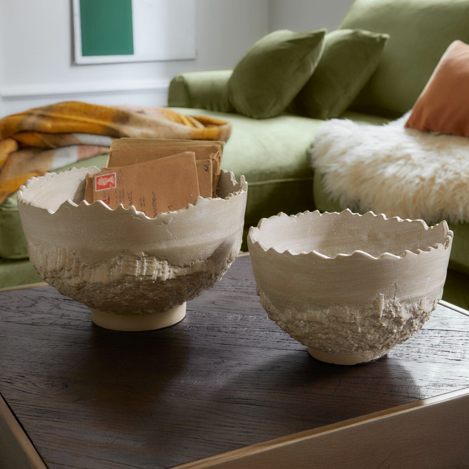Set de 2 cuencos Alvendra Dos cuencos de cerámica beige con textura rugosa y borde ondulado sobre mesa de madera