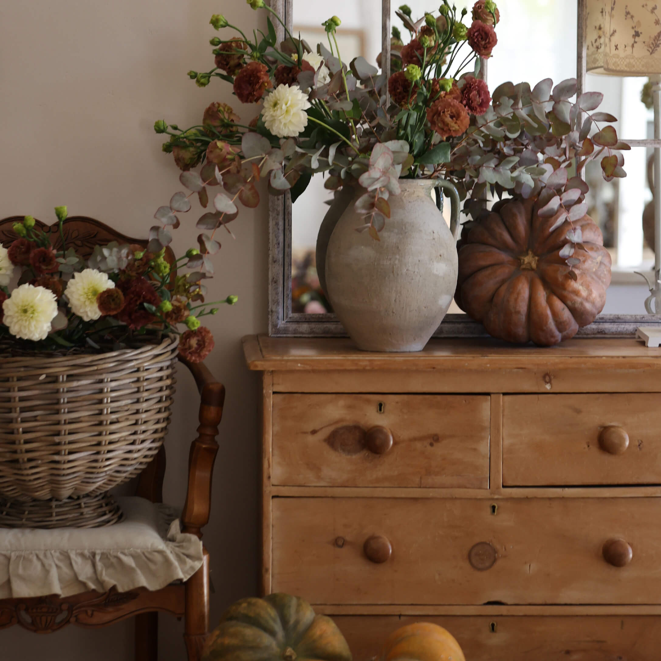 Cómoda rústica de madera con jarrón de barro, ramo otoñal y calabazas decorativas en ambiente acogedor
