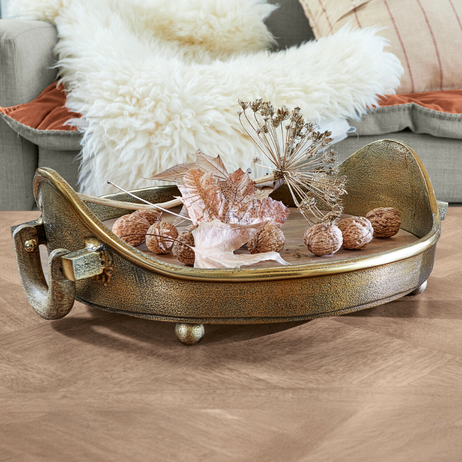 Bandeja Louvil Bandeja decorativa redonda de metal color oro envejecido con nueces y hojas secas sobre mesa de madera