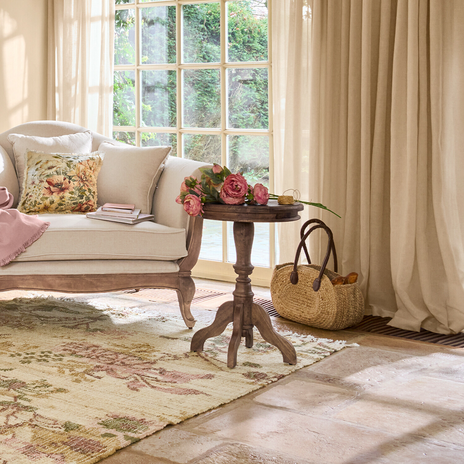 Sala acogedora con sofá beige, mesa de madera y flores sobre alfombra con diseño floral