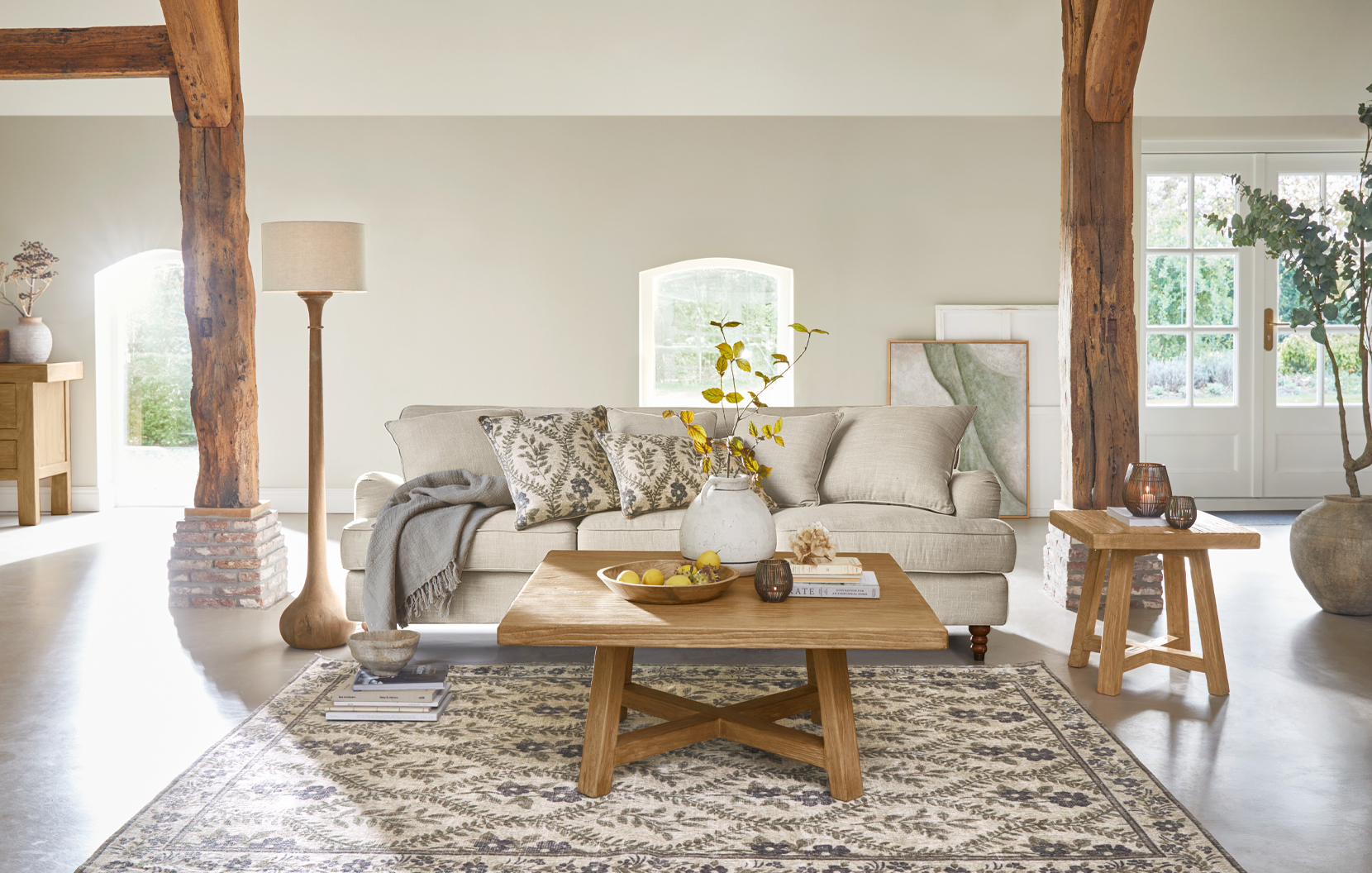 Acogedora sala de estilo rústico con sofá beige, mesa de madera y alfombra con motivos naturales