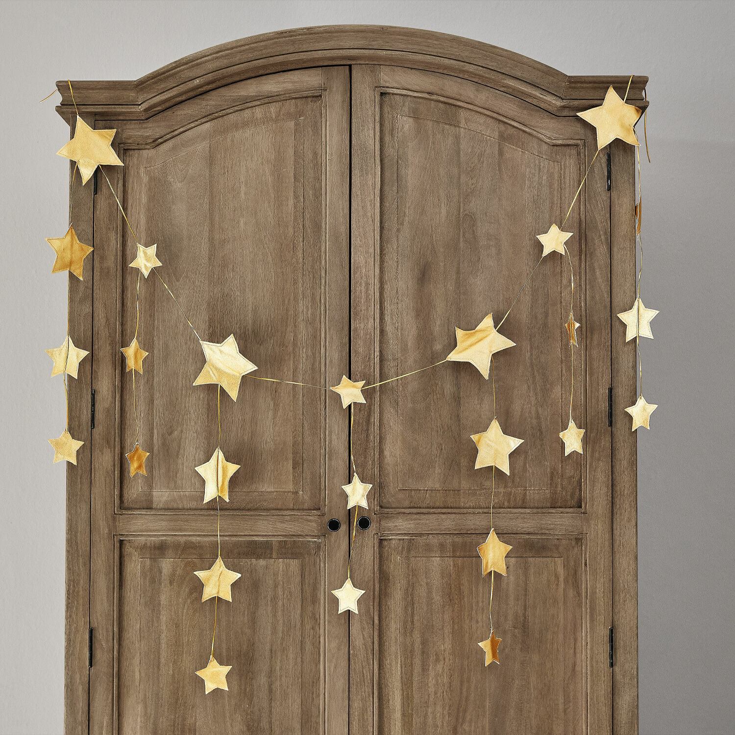 Garland Étoilin Guirnalda de estrellas doradas colgada en un armario de madera, decoración navideña para el hogar