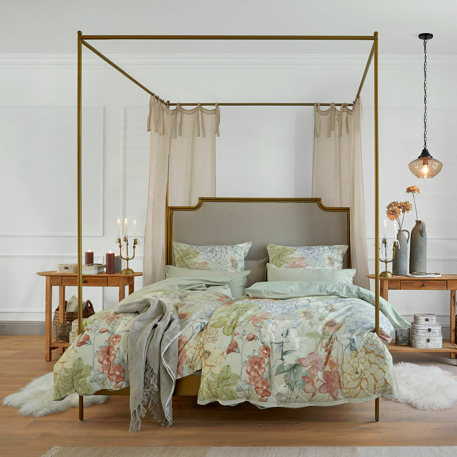 Cama con dosel de latón con ropa de cama floral y cortinas beige en dormitorio elegante