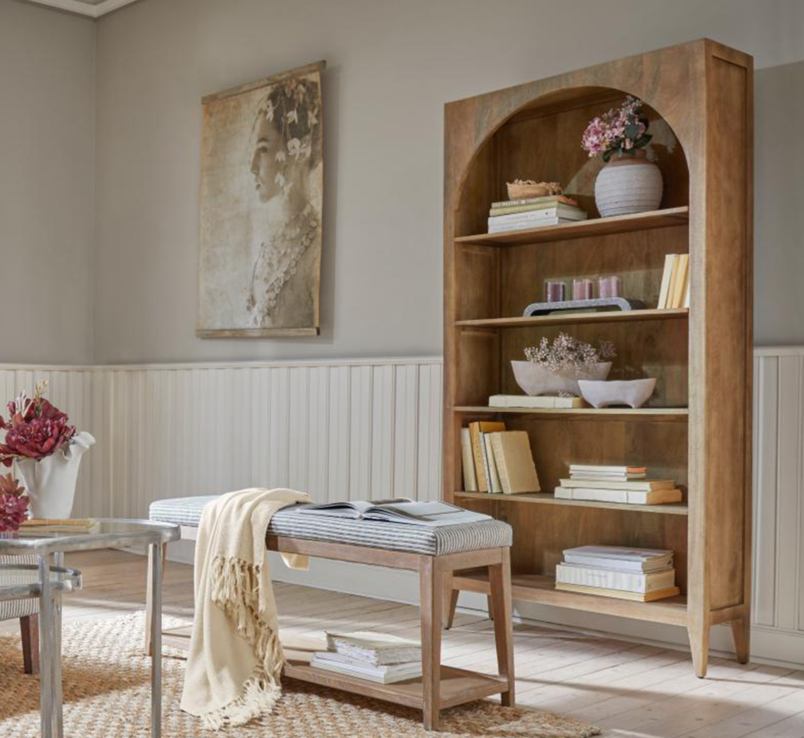 Estantería de madera con arco, decoraciones y libros en salón luminoso y natural