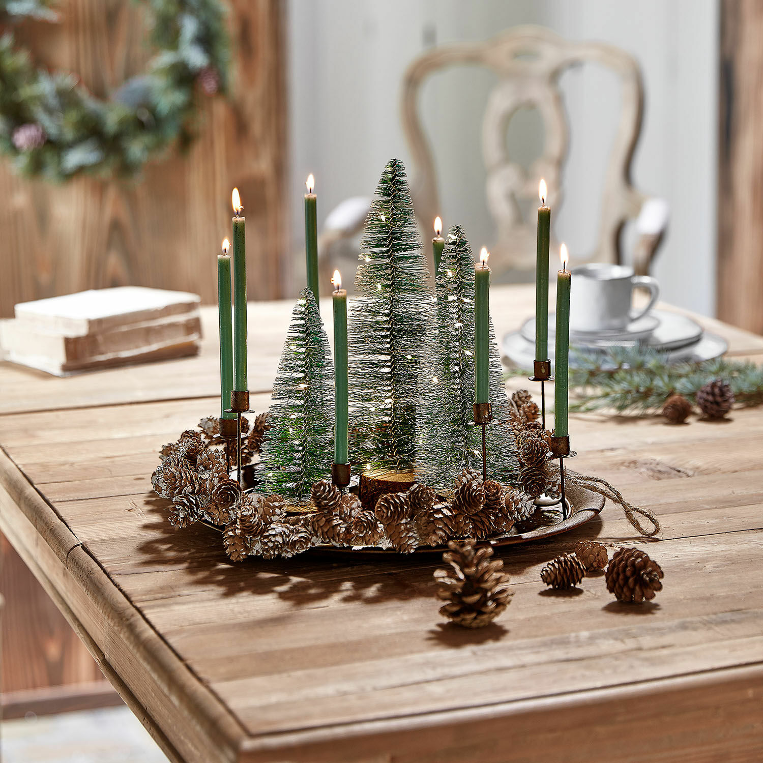 Set de 3 árboles LED decorativos Thalindra Corona decorativa navideña con velas verdes y piñas sobre mesa de madera
