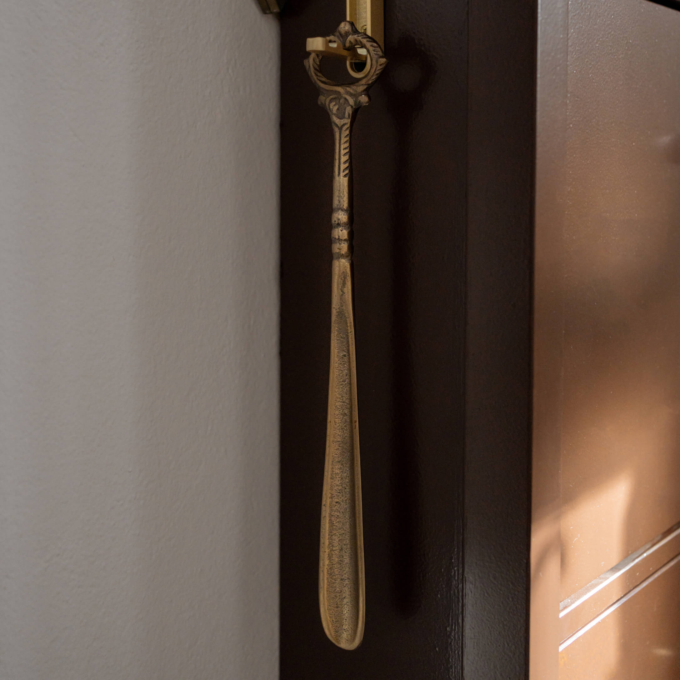 Calzador metálico dorado con mango decorativo, herramienta práctica para el hogar